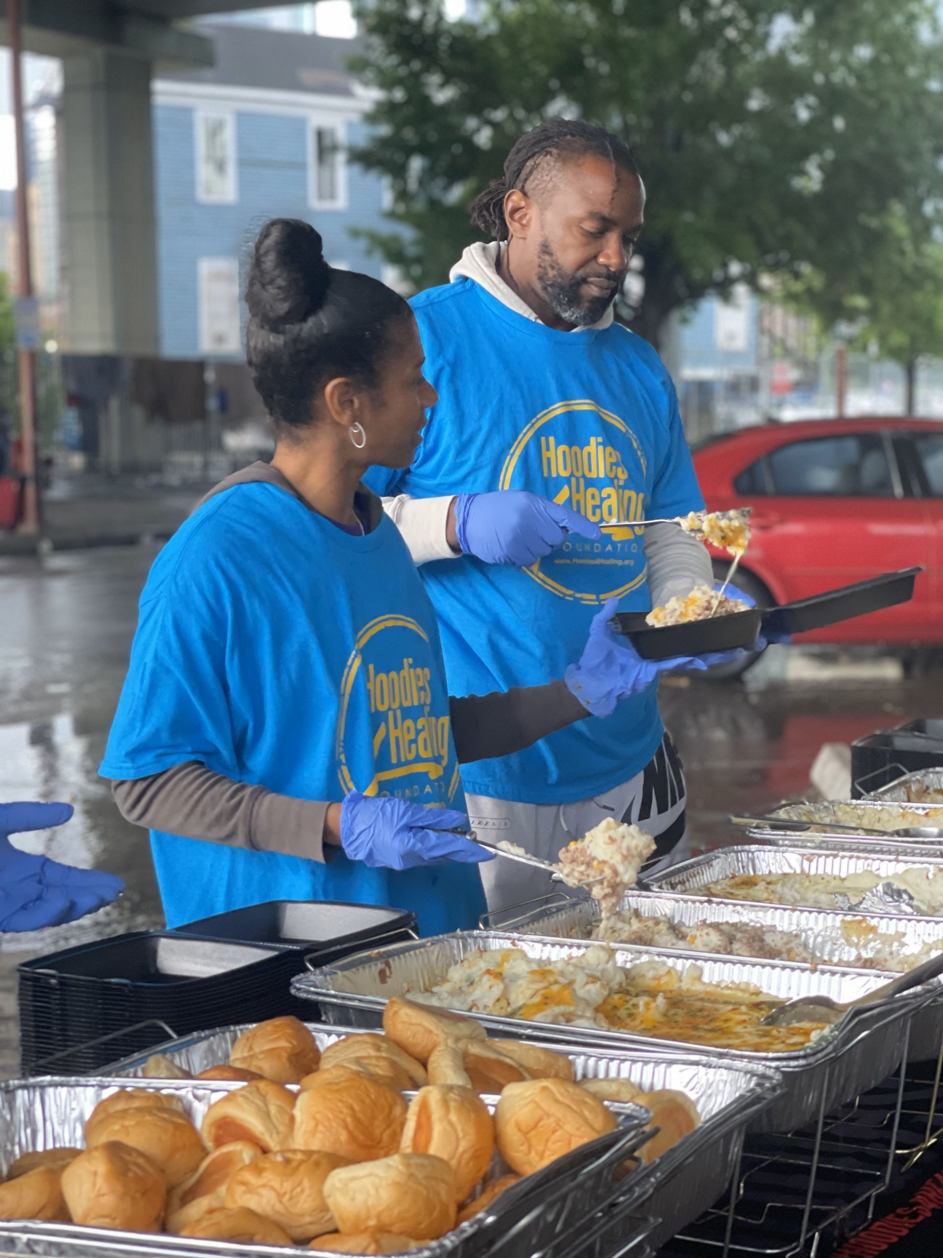 A man and a woman are serving food to a group of people.