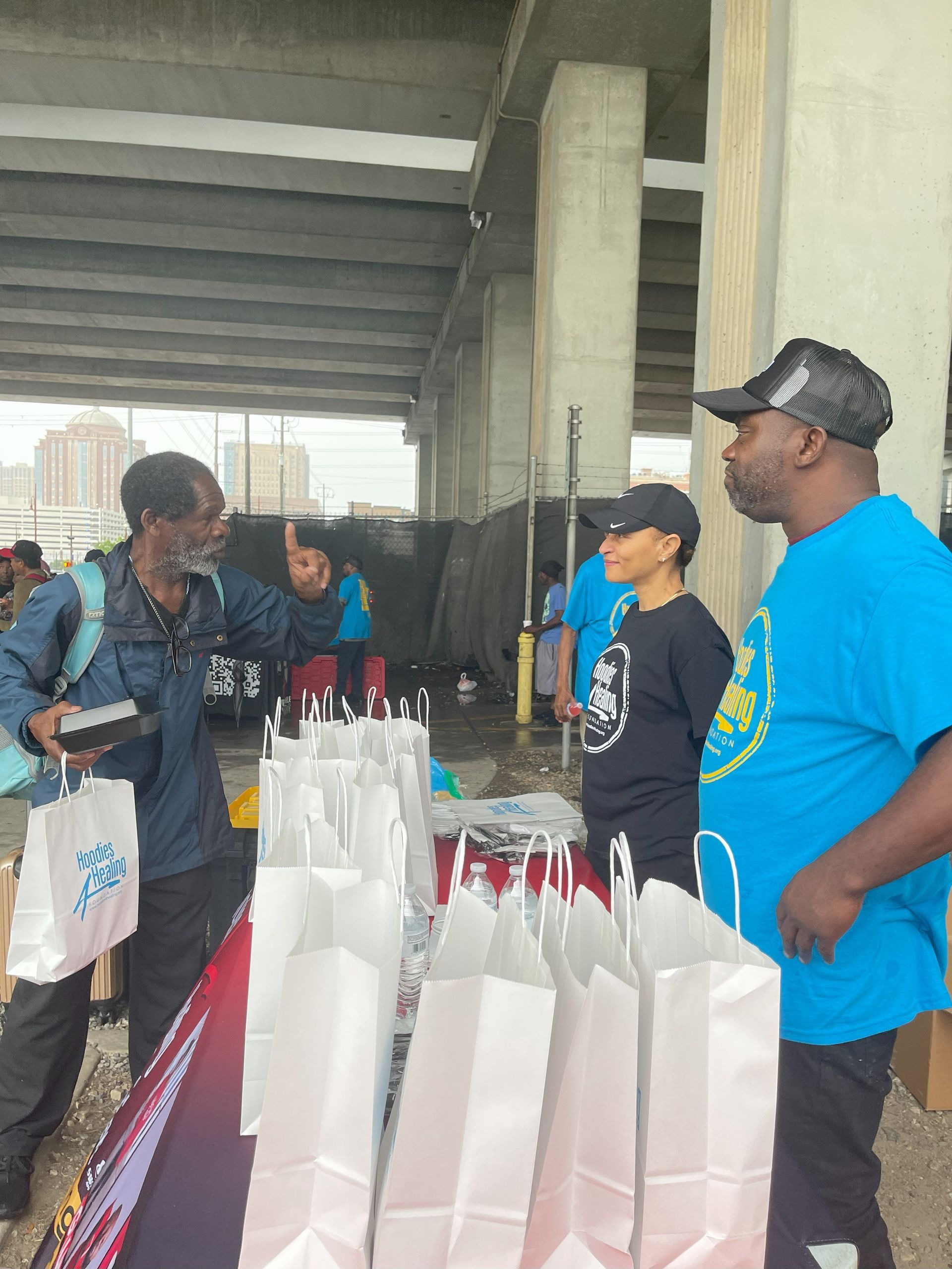A group of people are standing around a table with bags on it.