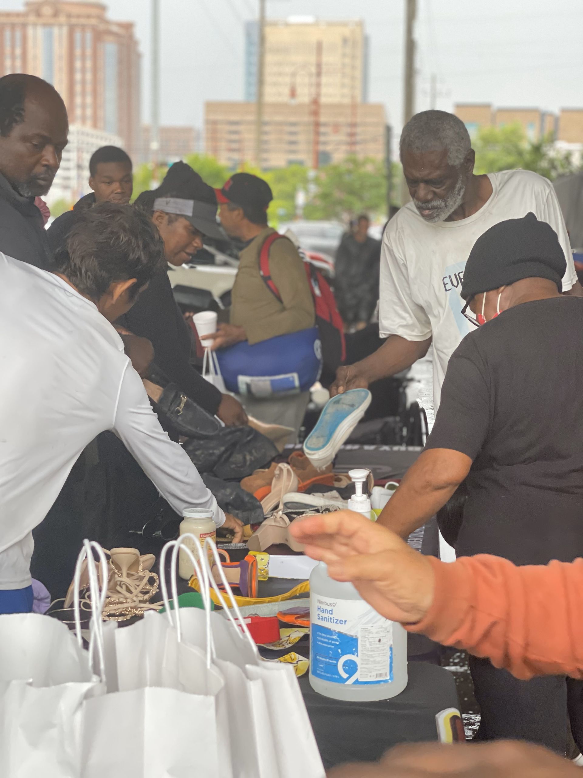A group of people are gathered around a table with a bottle of hand sanitizer on it