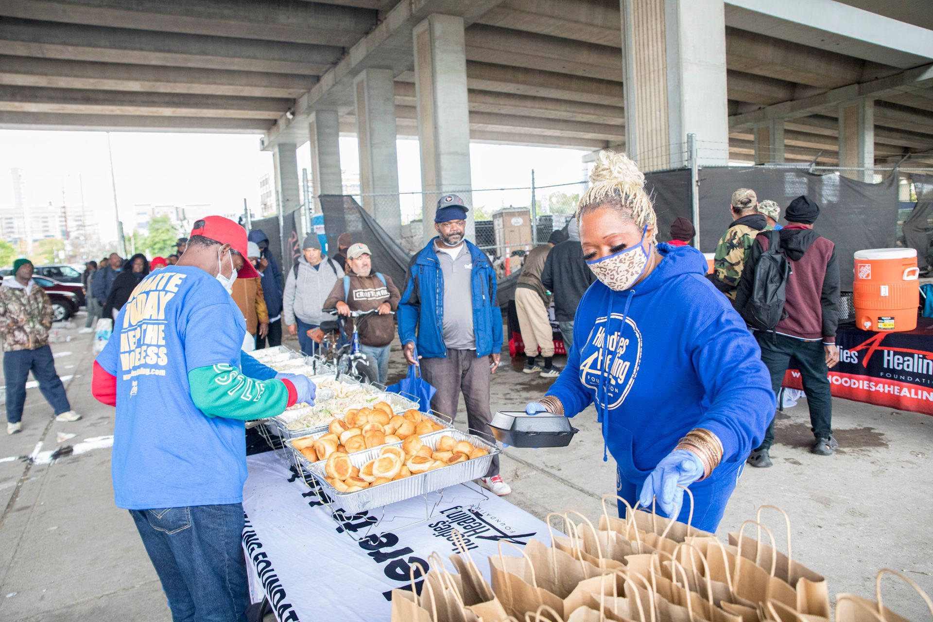A group of people are standing around a table serving food.