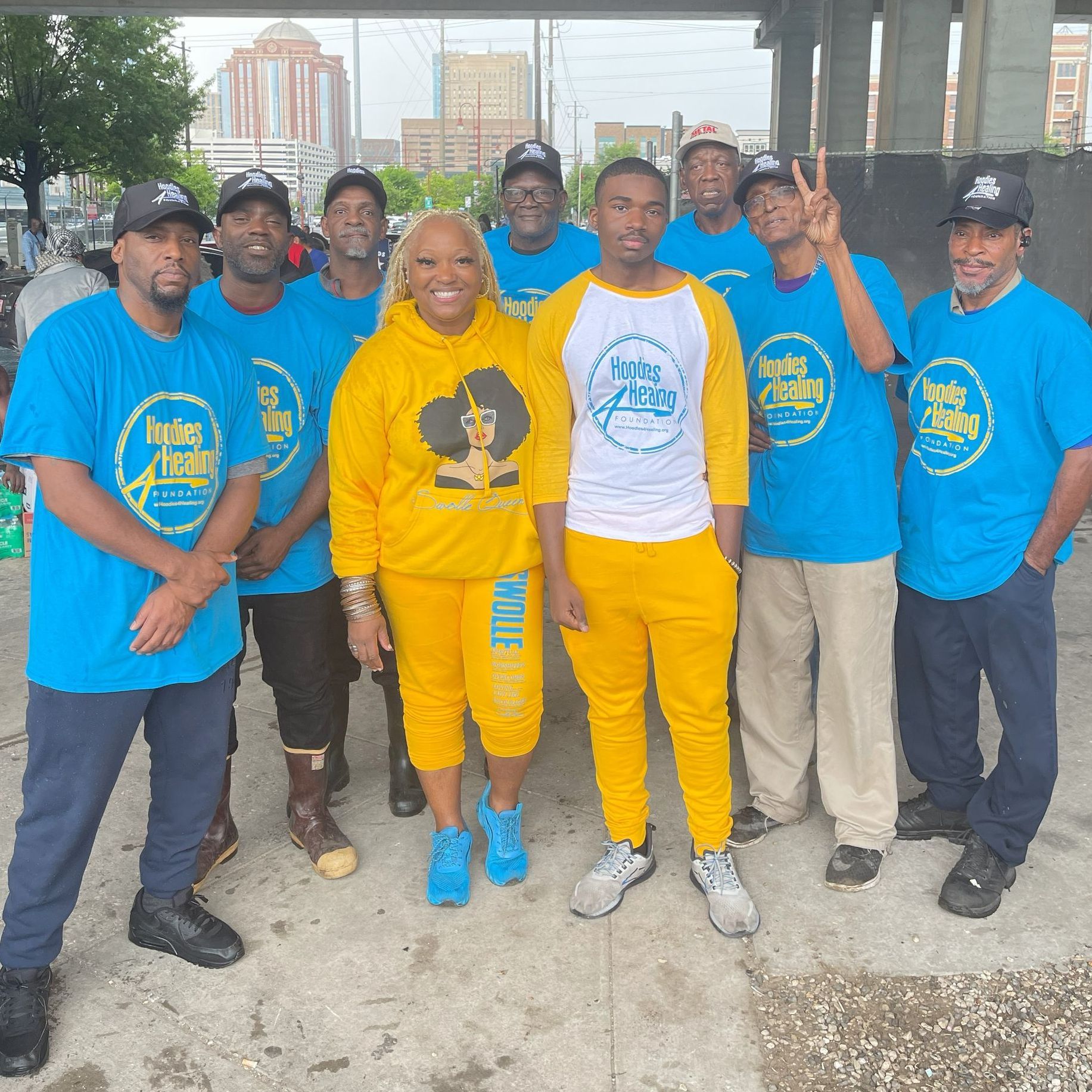 A group of people wearing blue shirts and yellow pants pose for a photo