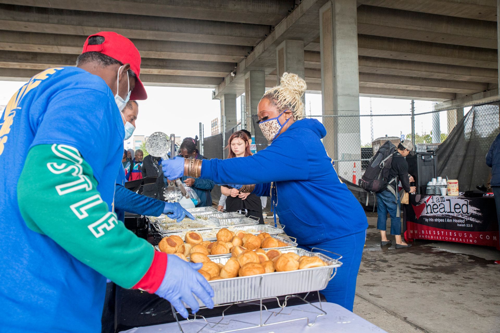 A man and a woman are serving food to a group of people.