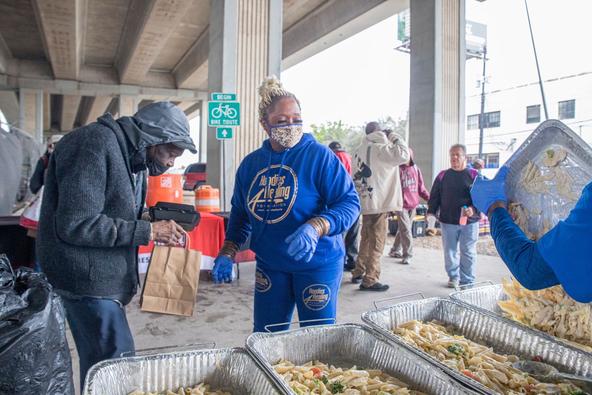 A group of people are standing around trays of food.