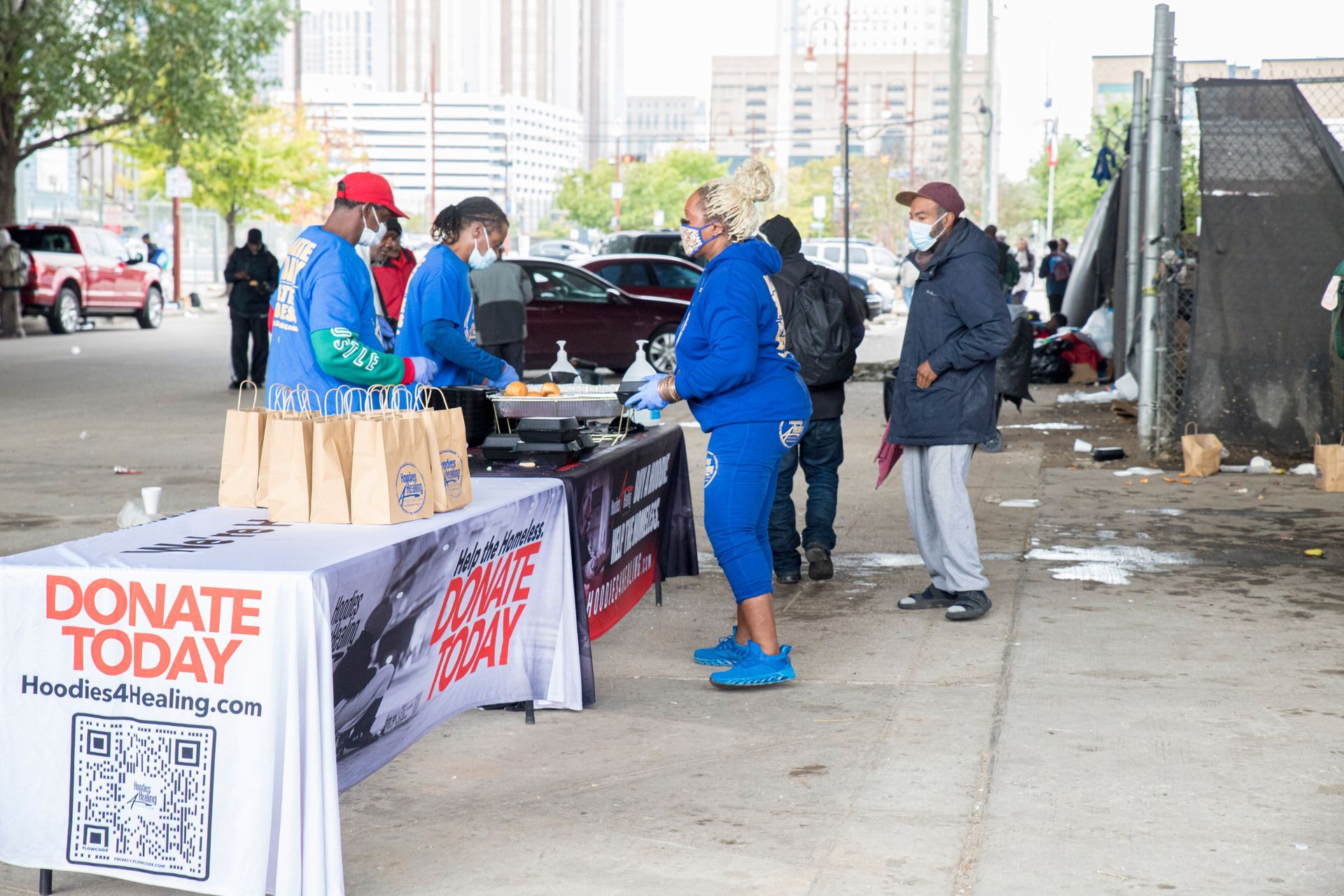 A group of people are standing around a table that says `` donate today ''.