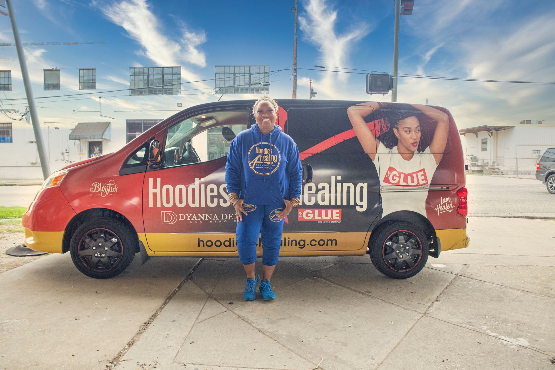 A man is standing in front of a van that says hoodies ealing on it.