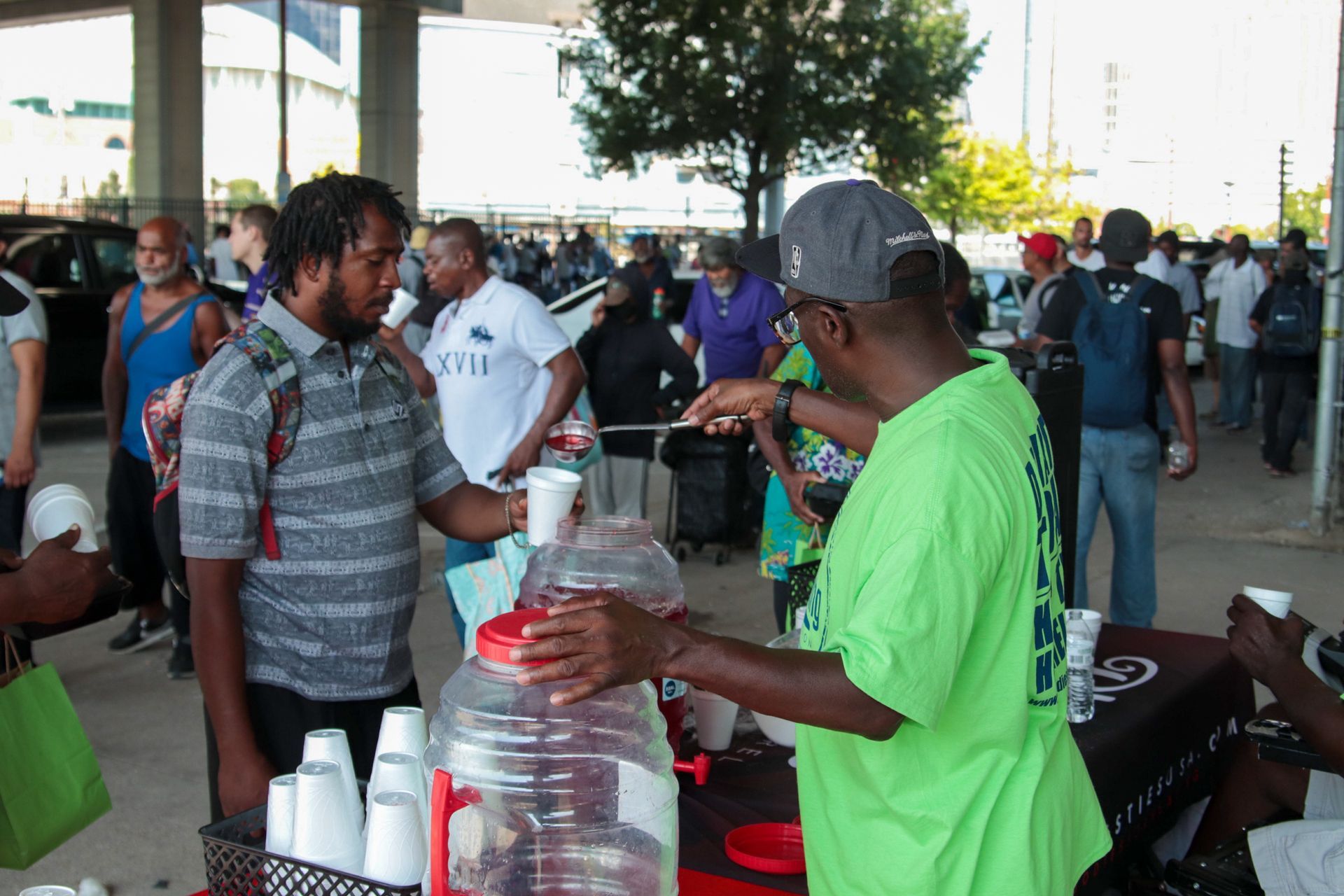 A man in a green shirt is serving drinks to a group of people.