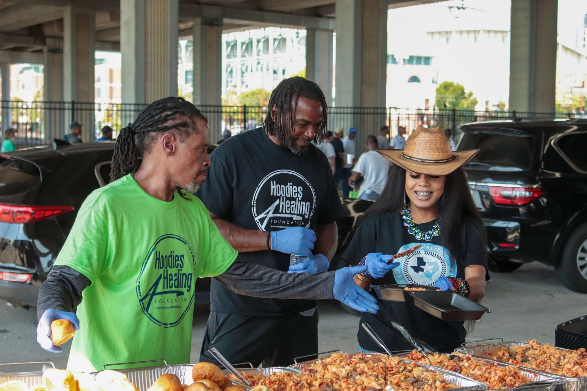 A group of people are preparing food in a parking lot.