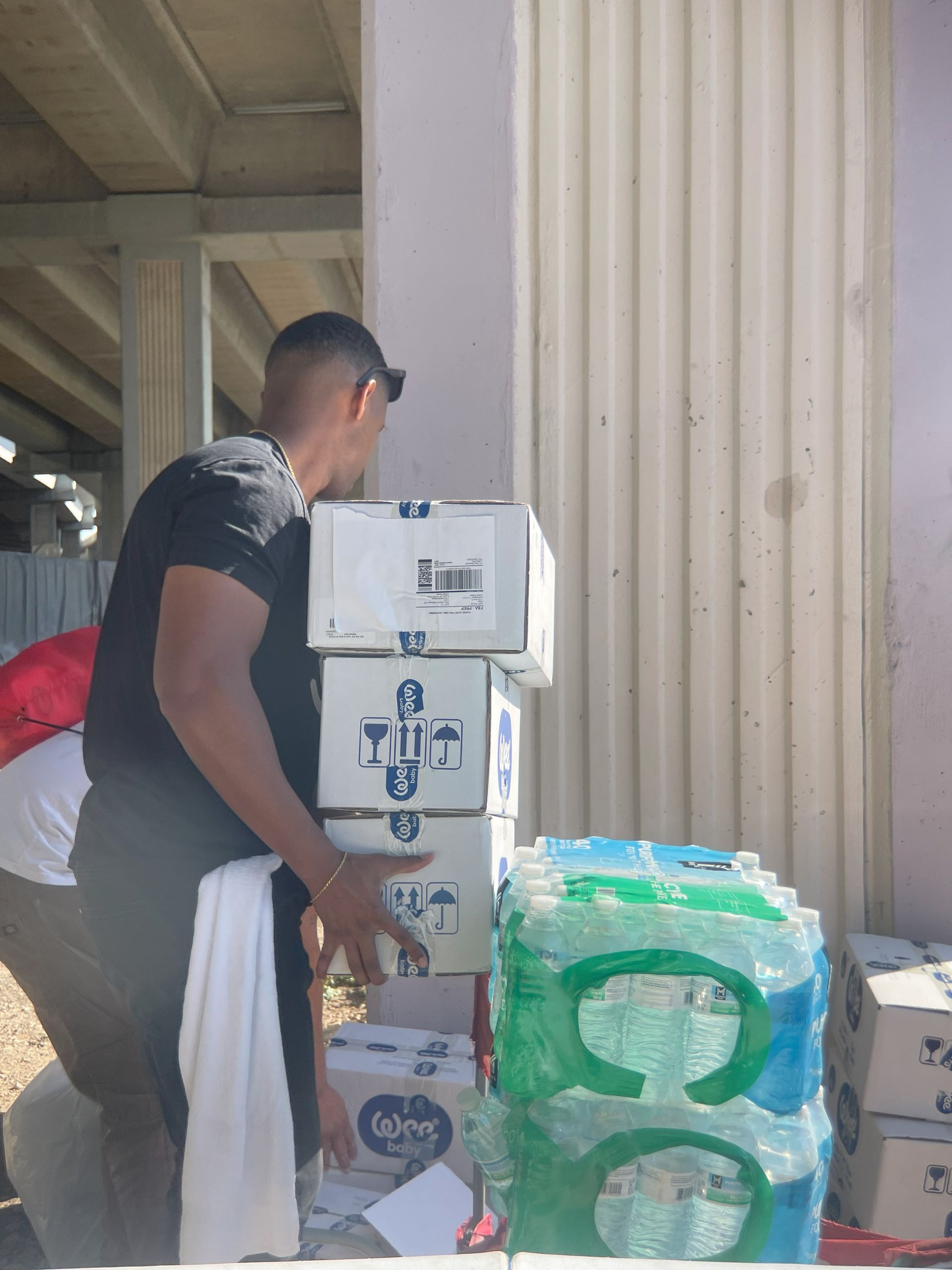 A man is standing next to a stack of boxes that say nue