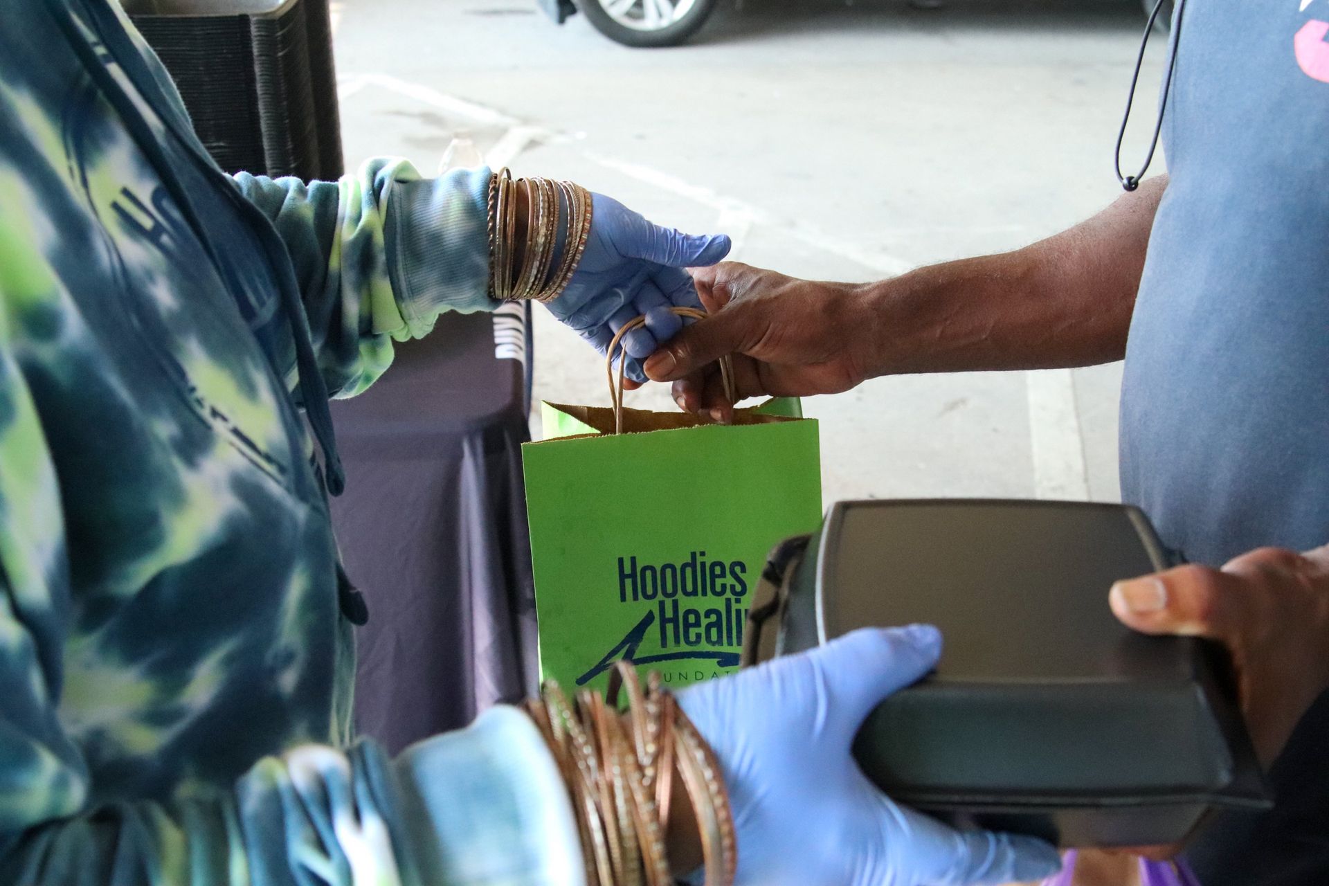 A person is holding a green bag that says hoodies heal