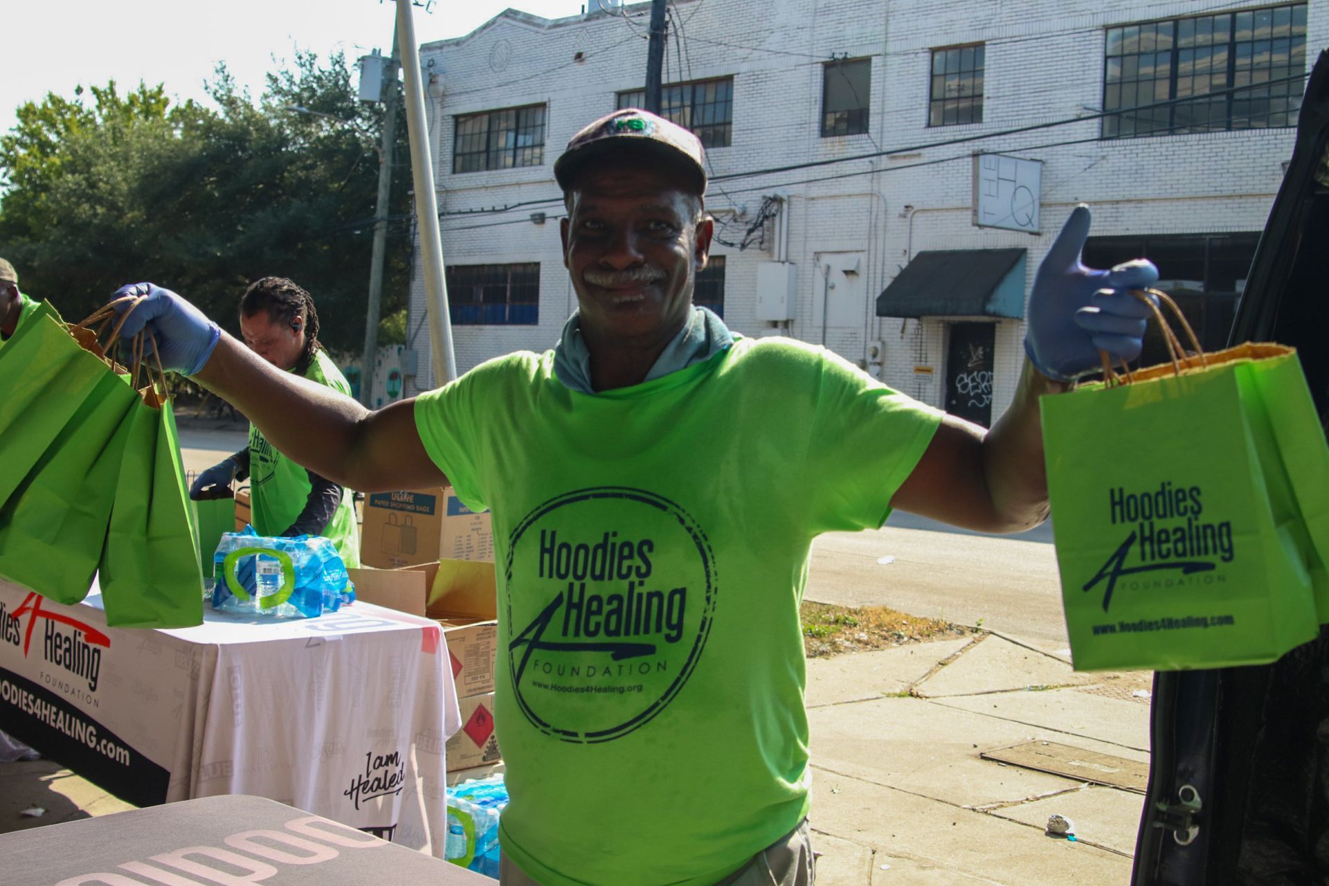 A man wearing a green shirt that says hoodies healing