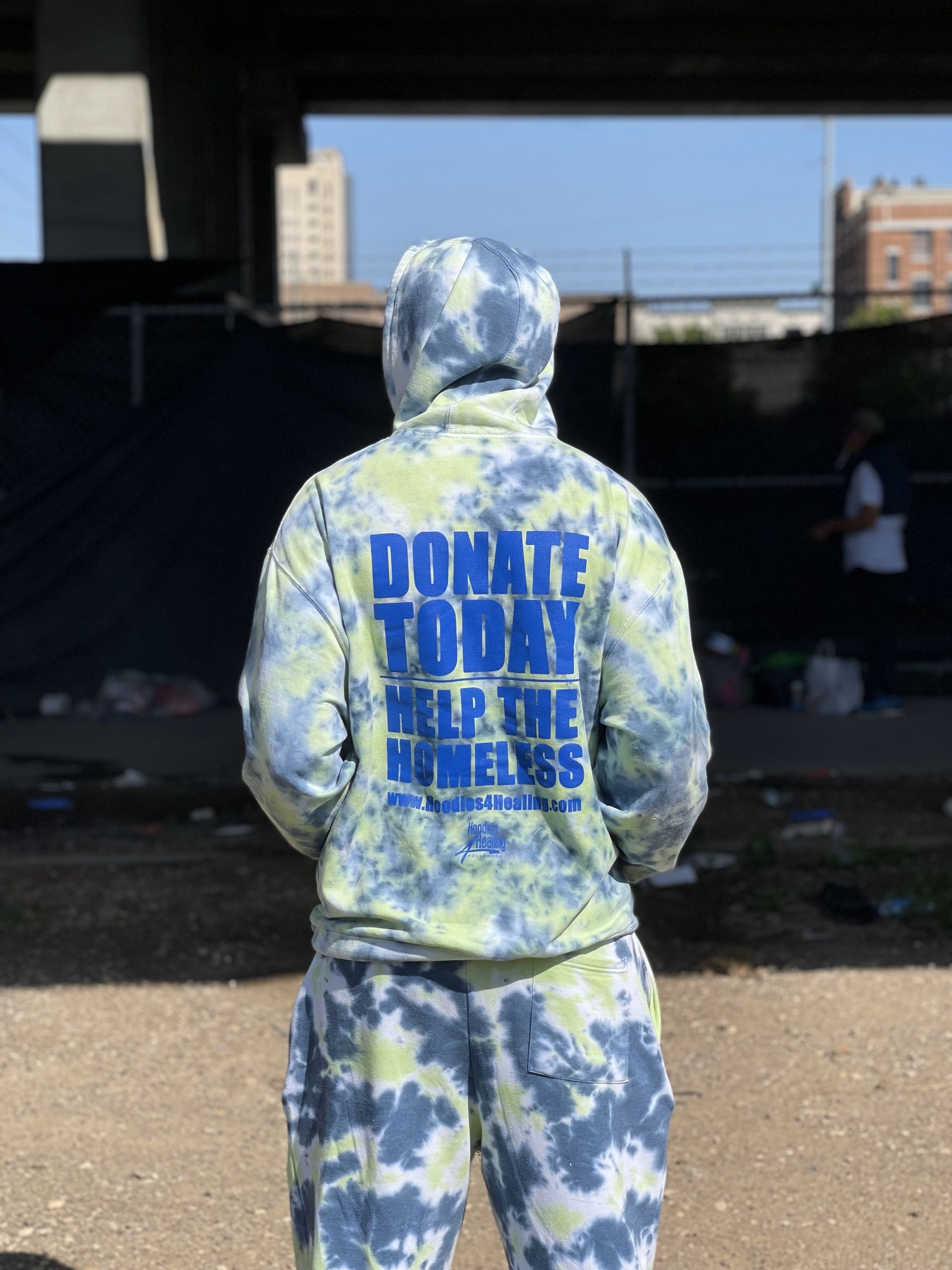A person wearing a tie dye hoodie that says donate today