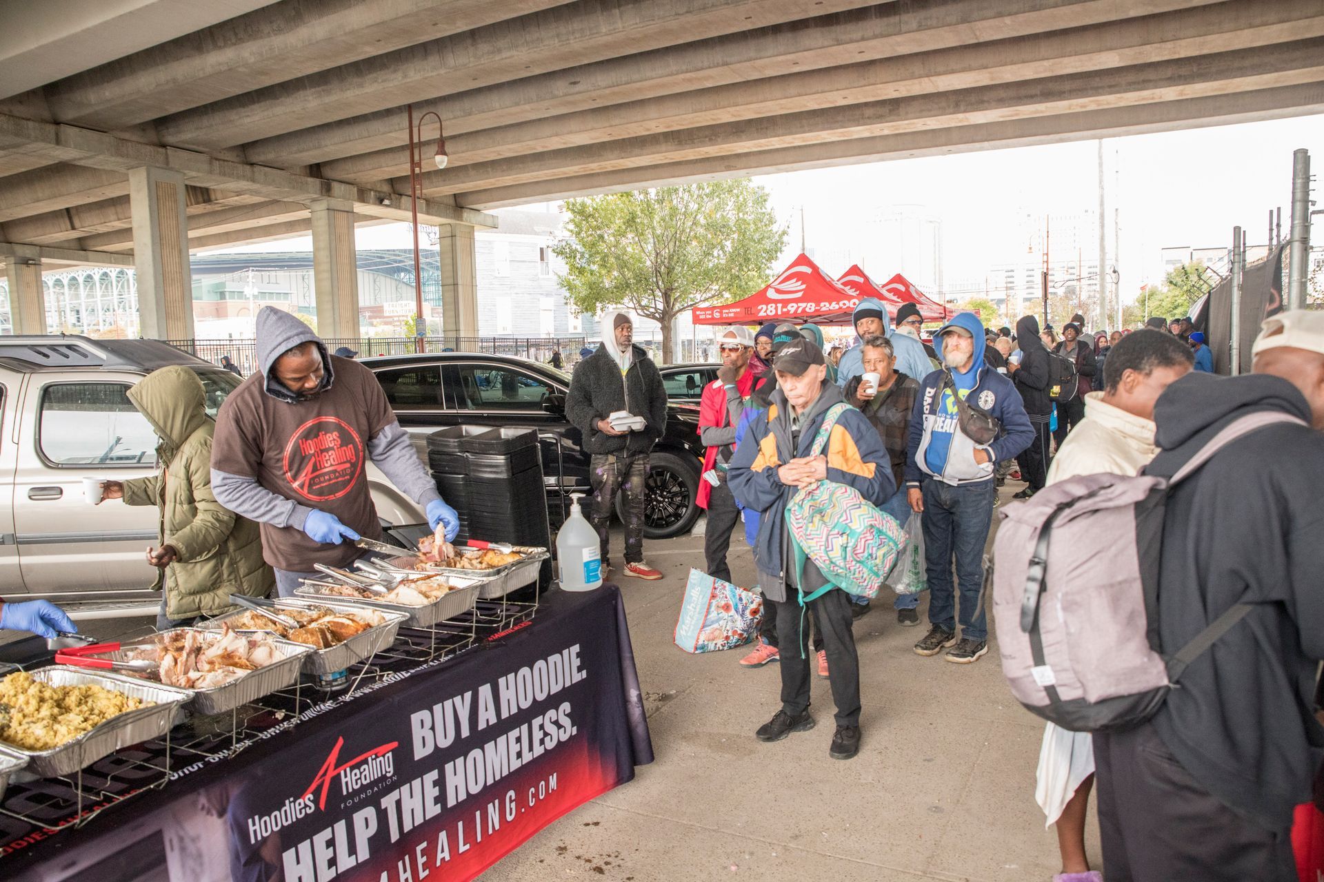 A group of people are standing around a table with food on it.