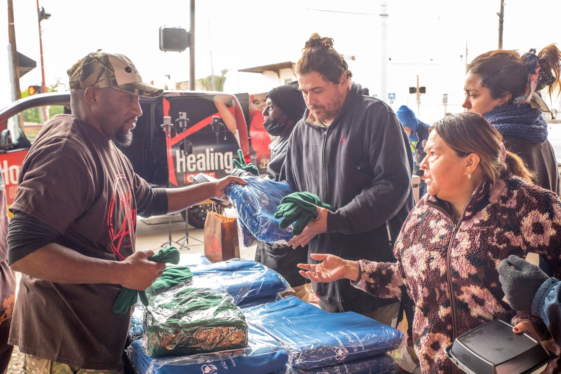 A group of people are standing around a table holding blankets.