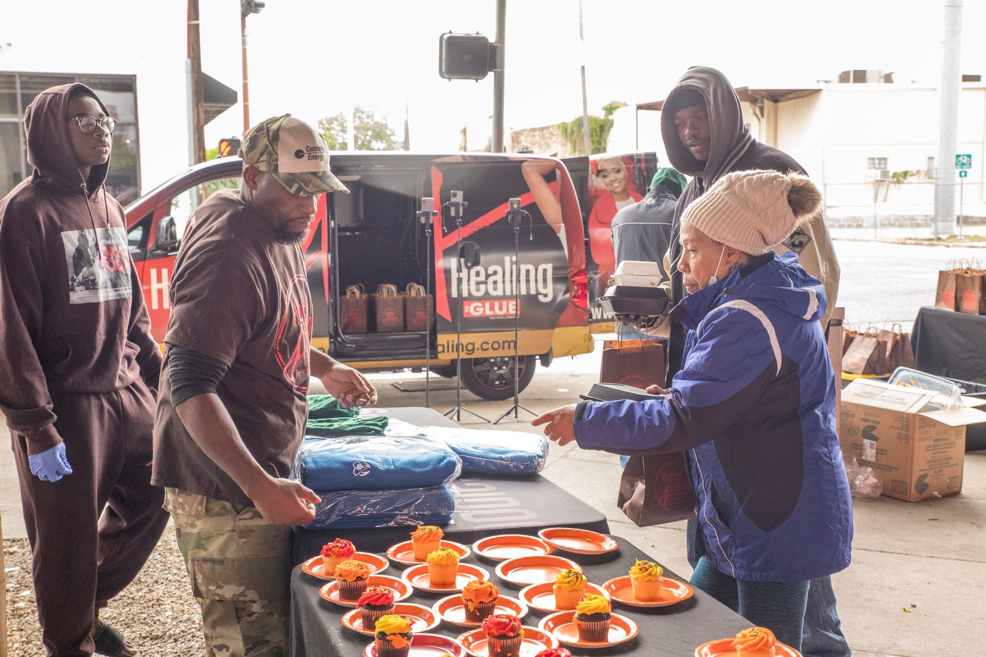 A group of people are standing around a table with plates of food.