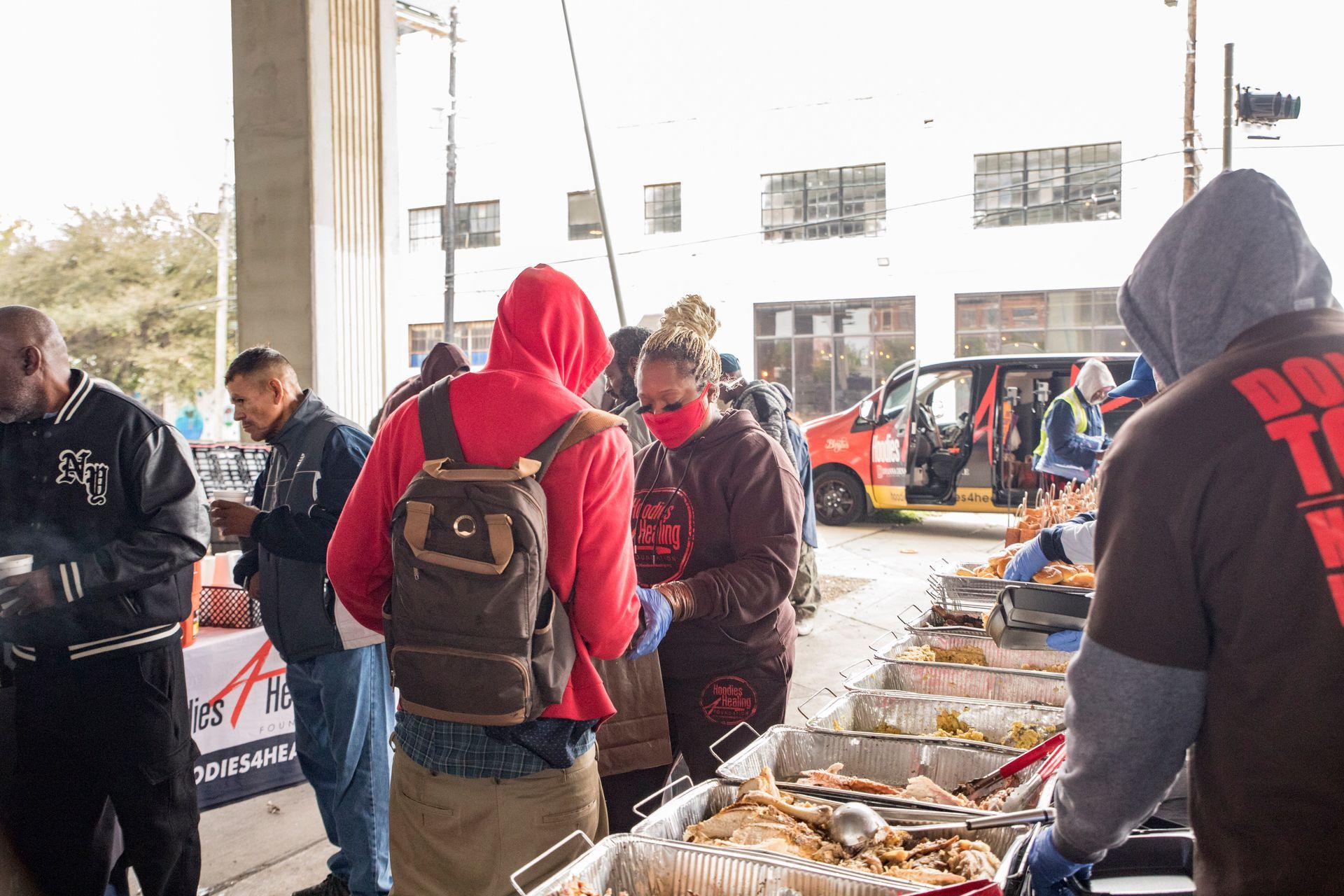 A group of people are standing around a table filled with food.