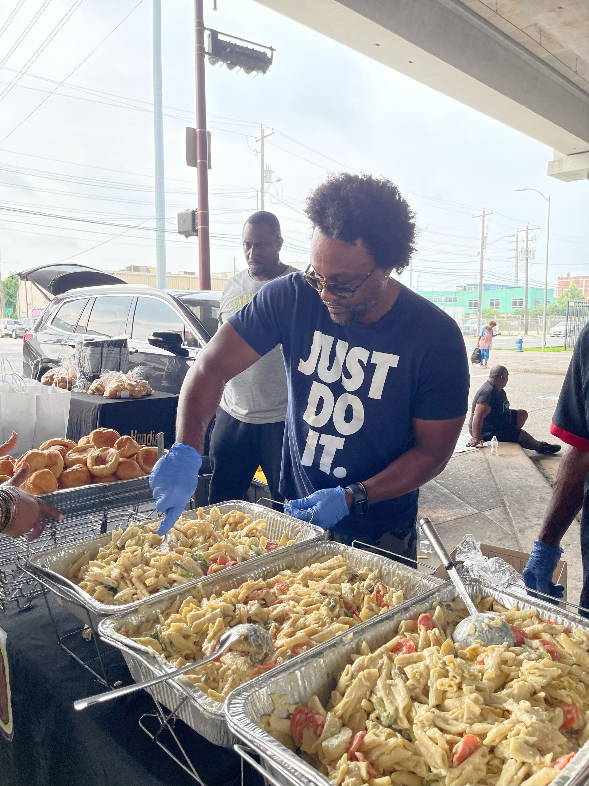 A man in a just do it shirt is serving food from a buffet table.