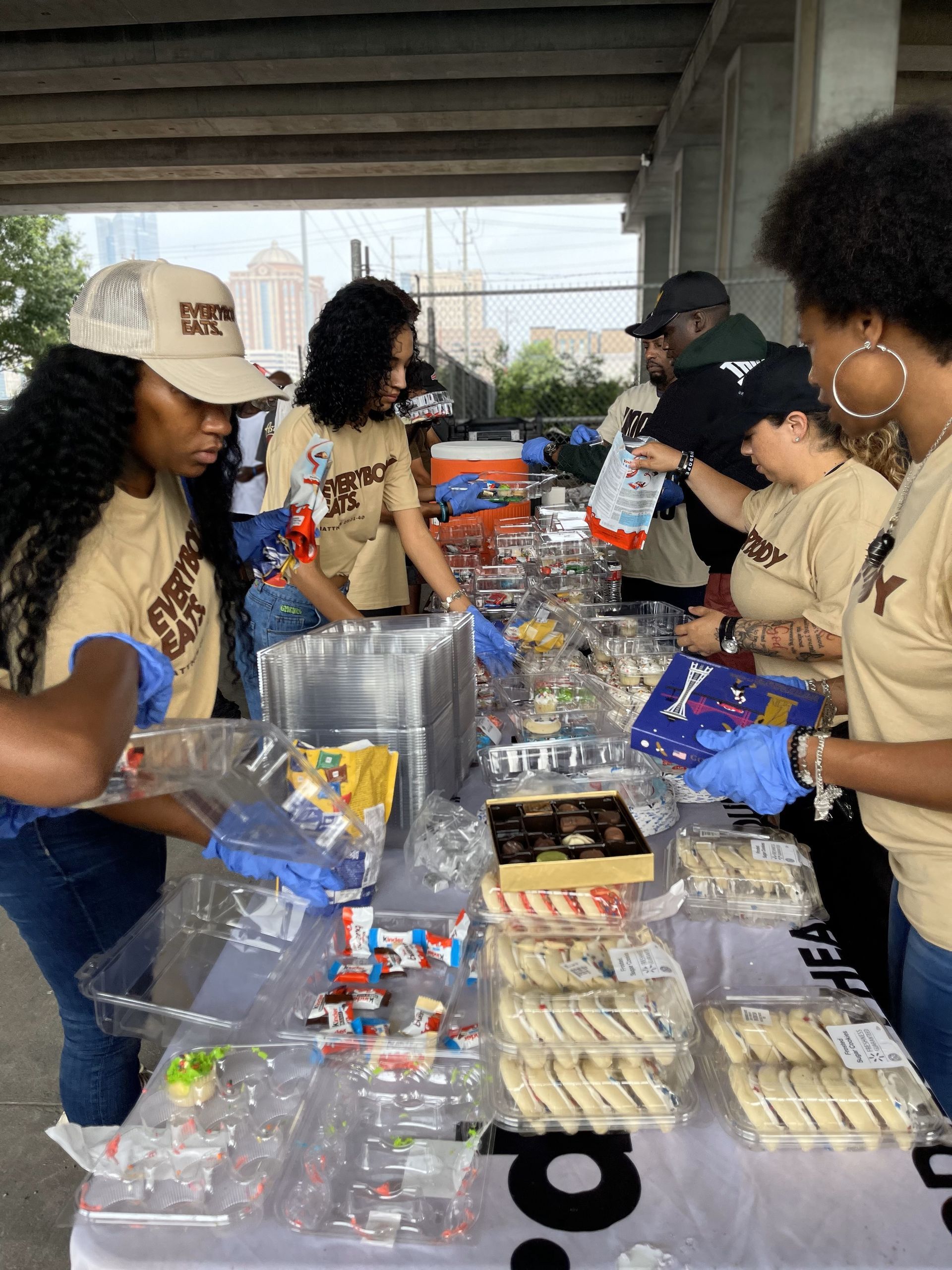 A group of people are standing around a table filled with food.