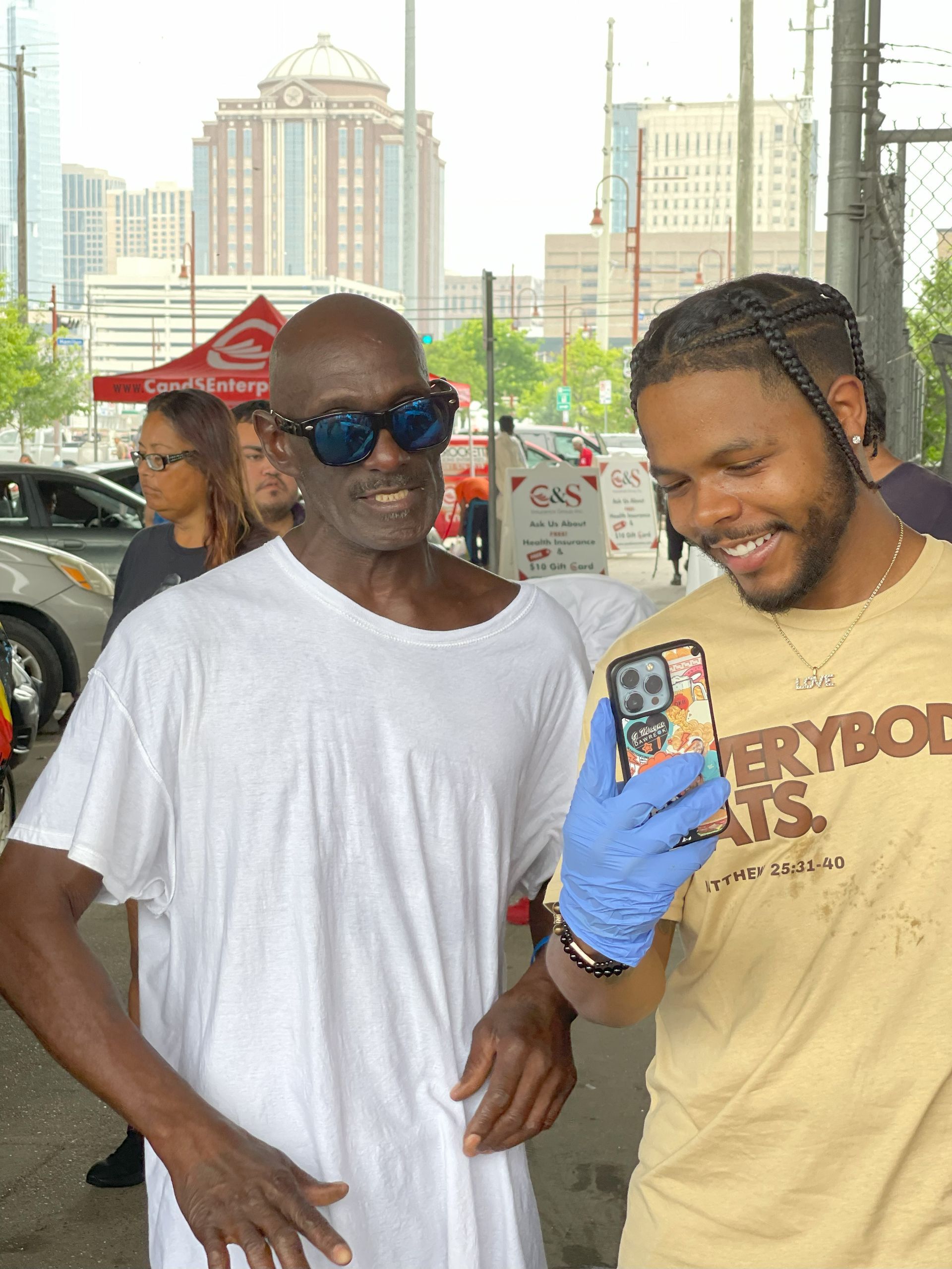 A man in a yellow shirt is taking a picture of another man in a white shirt.