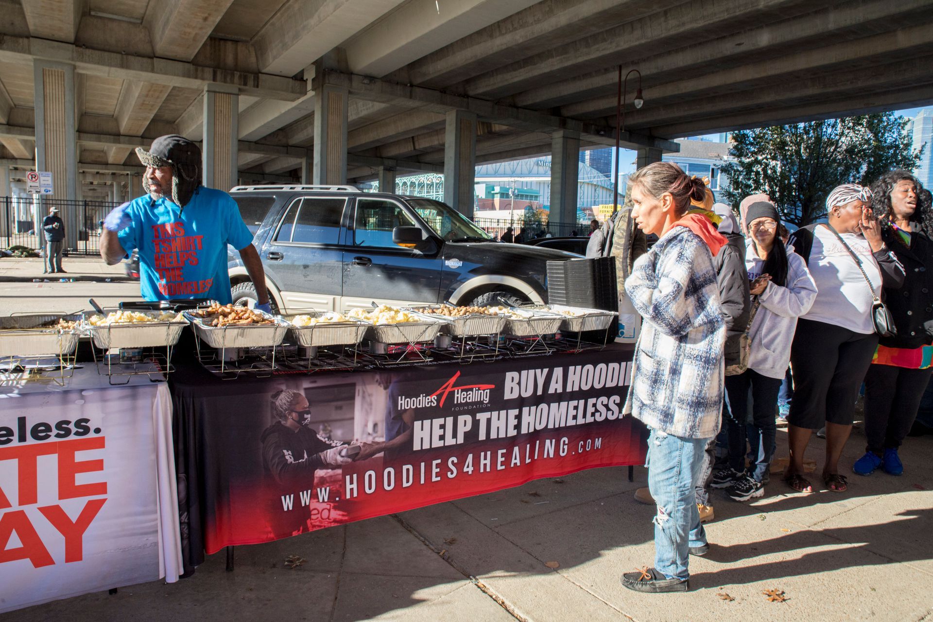 A group of people are standing around a table with food on it.