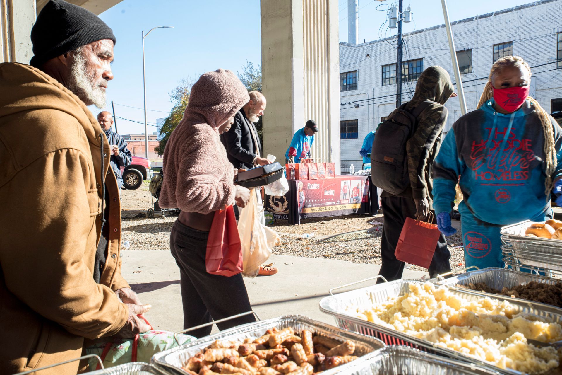 A group of people are standing around a table of food.
