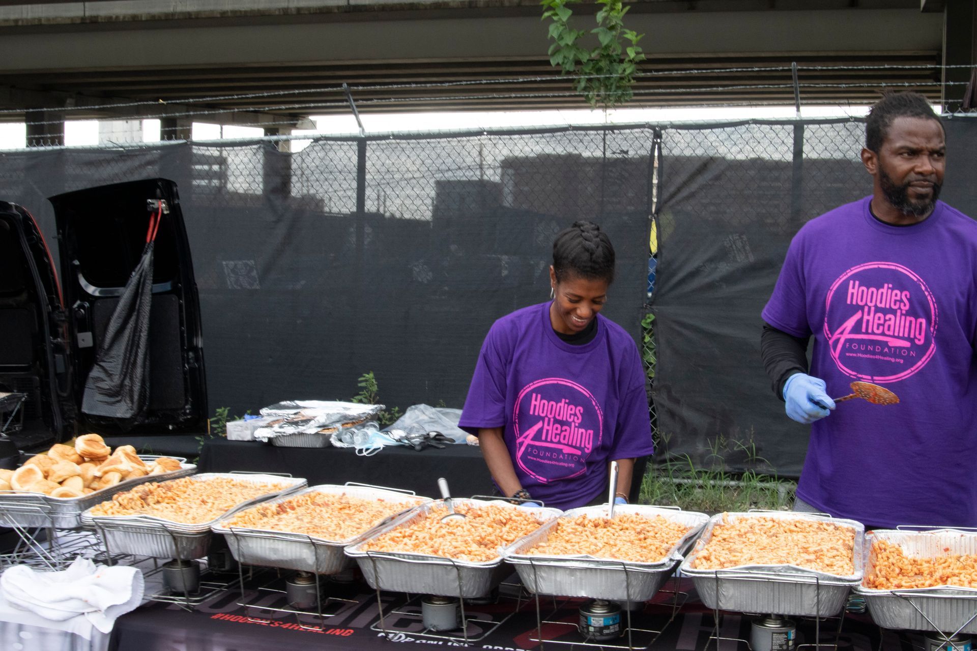 A man and a woman wearing purple shirts serving food
