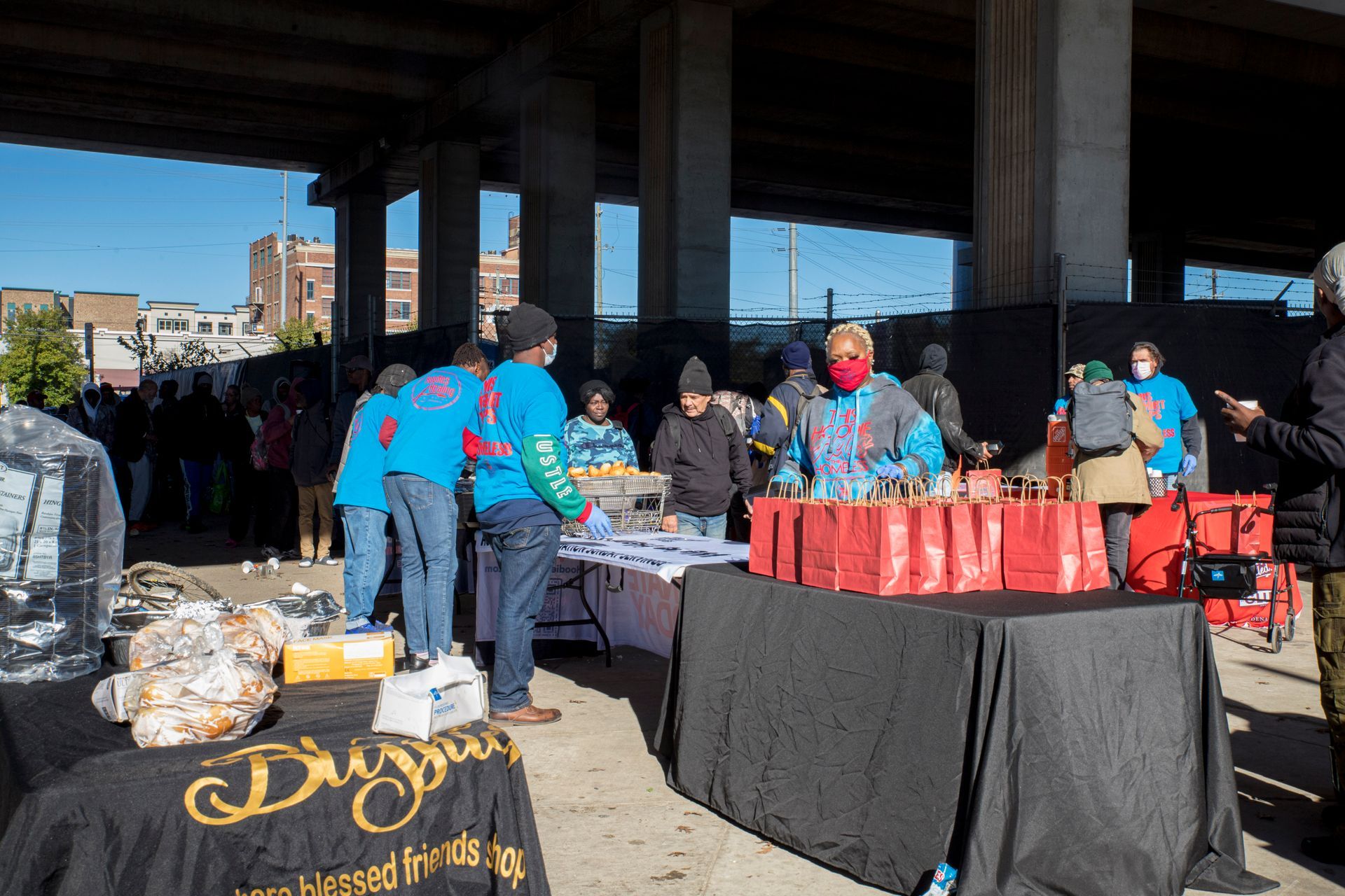 A group of people are standing around a table with bags on it.
