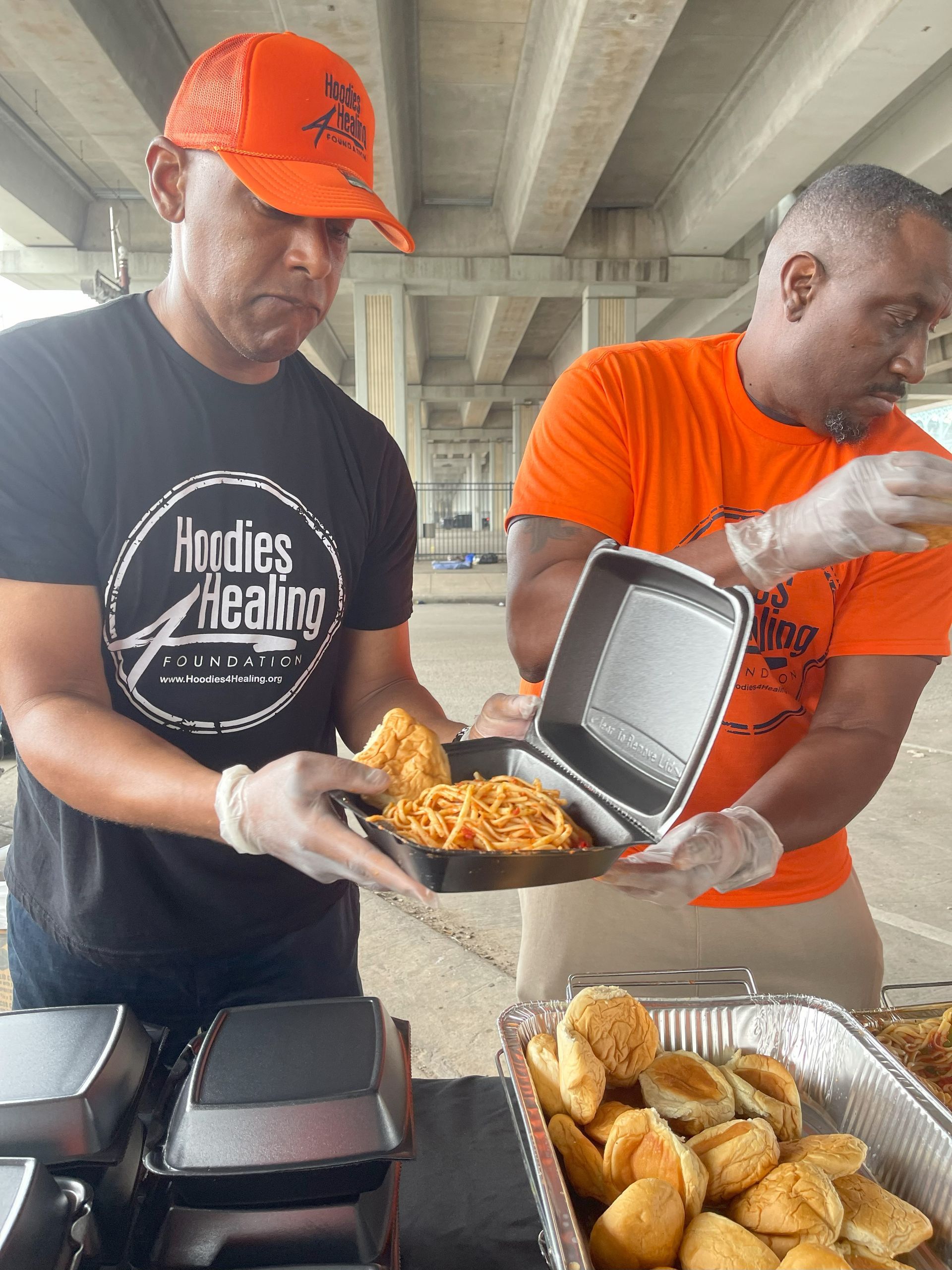Two men are standing next to each other holding trays of food.