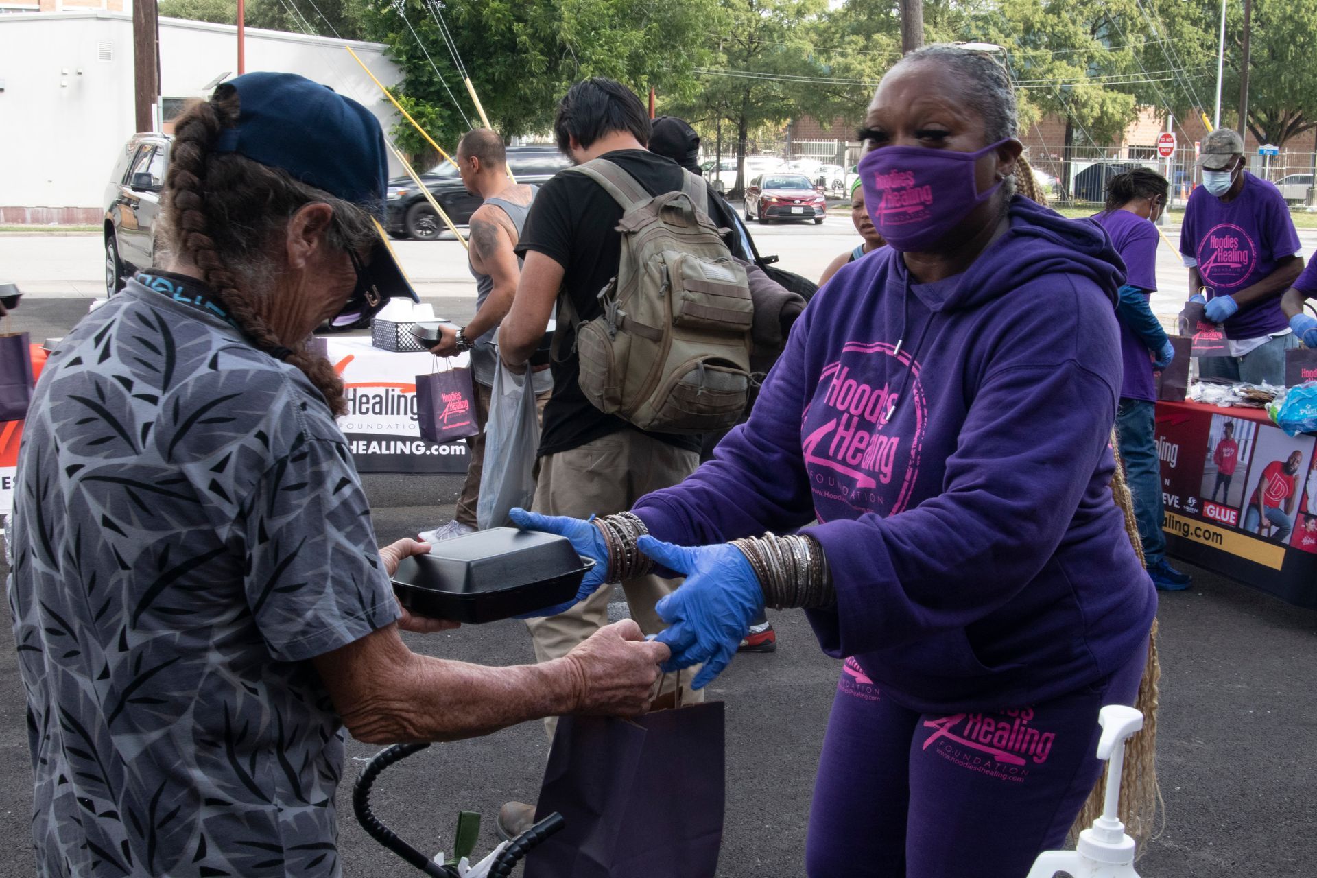 A woman wearing a mask is giving food to another woman.