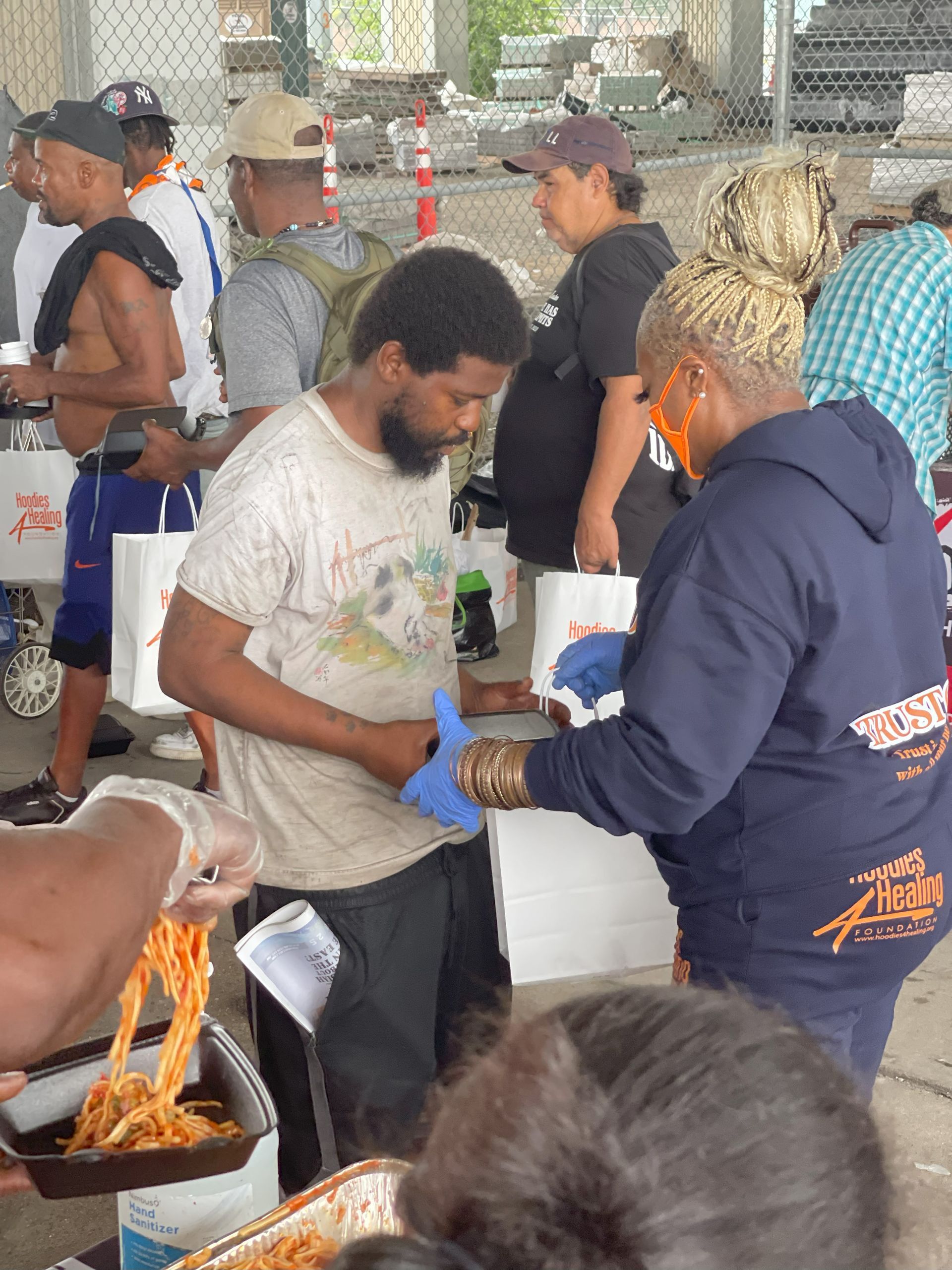 A group of people are standing around a table with a woman wearing a sweatshirt that says ' the help ' on it