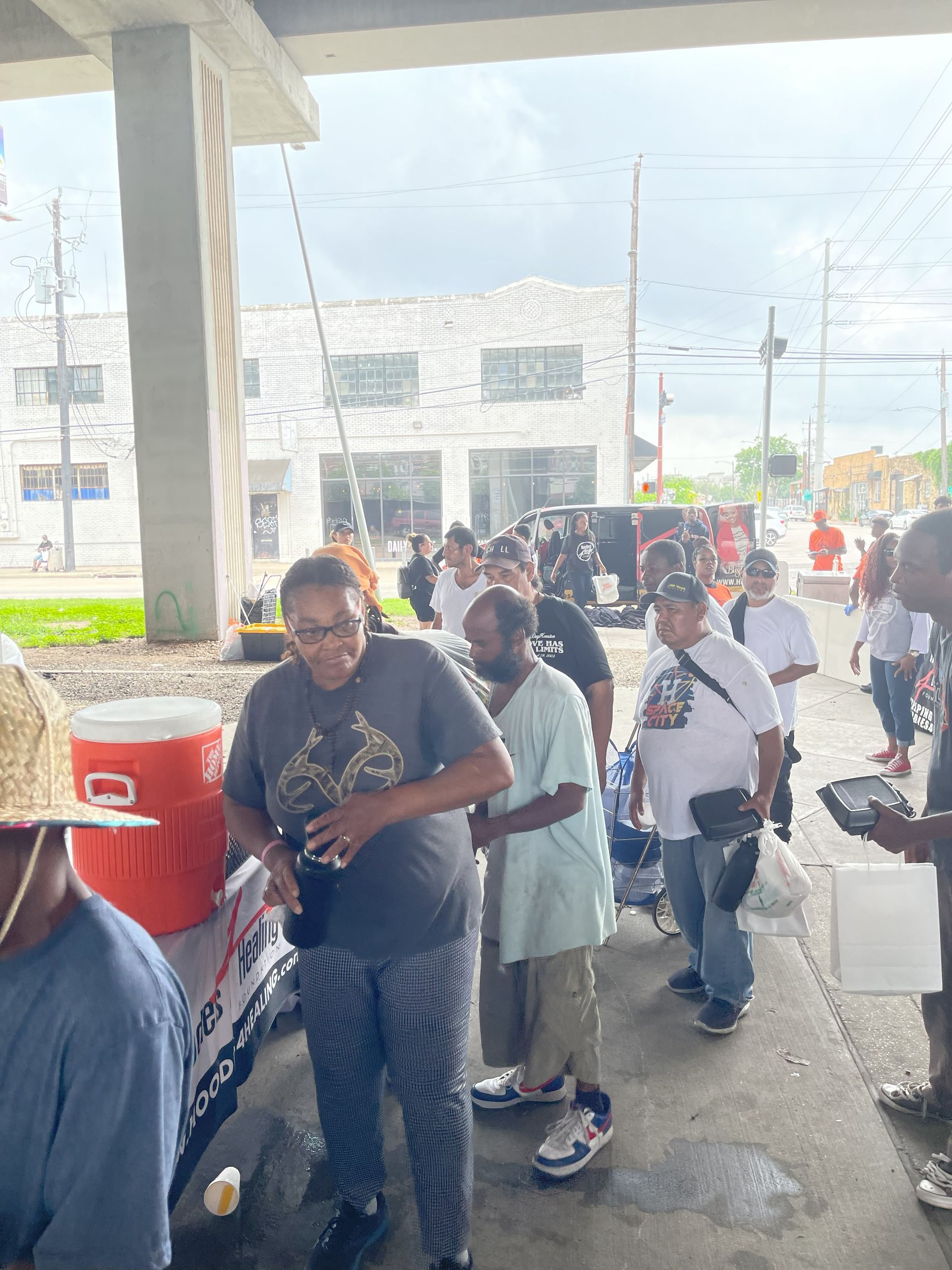 A group of people are standing in a line under a bridge.