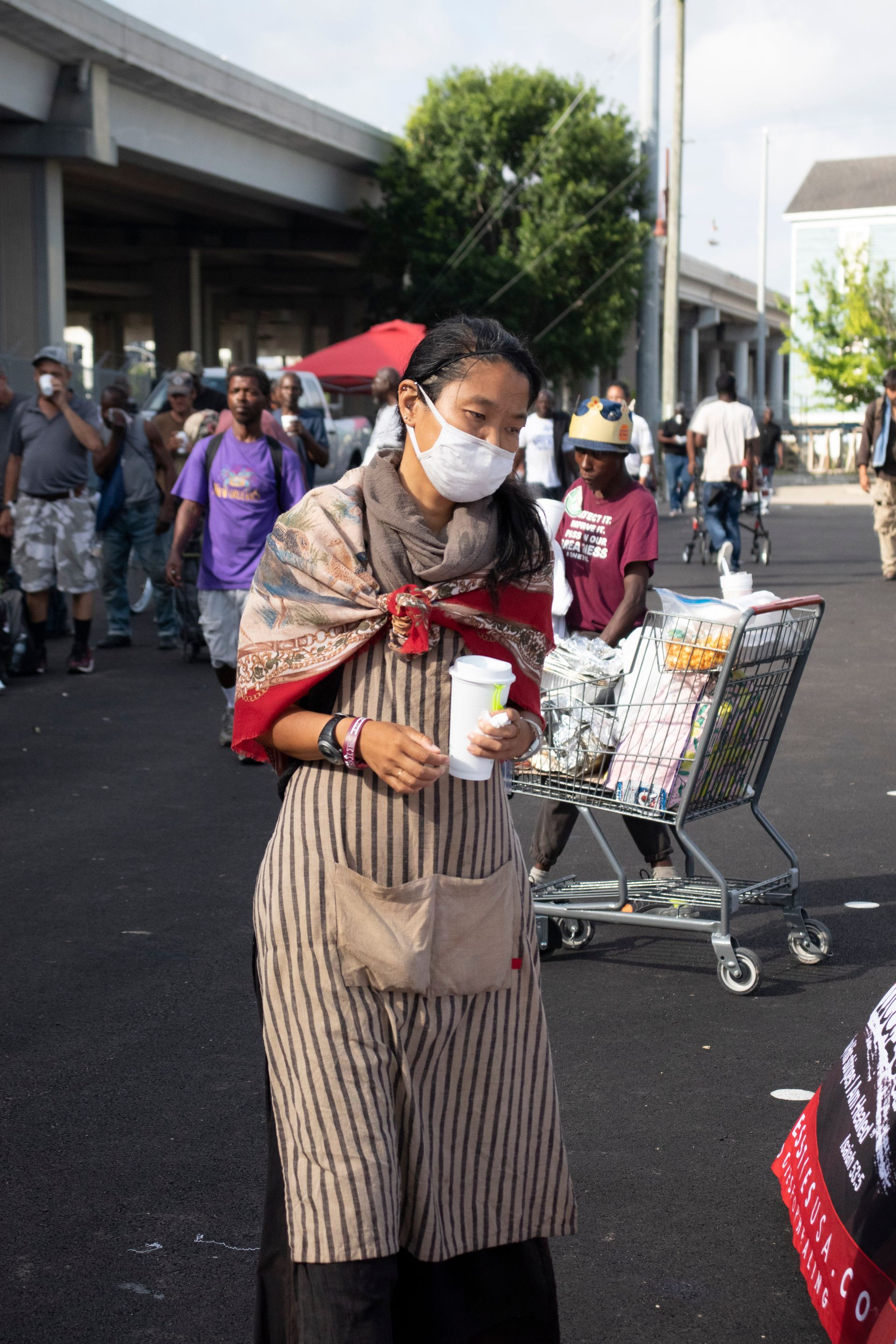 A woman wearing a mask is standing in front of a shopping cart.