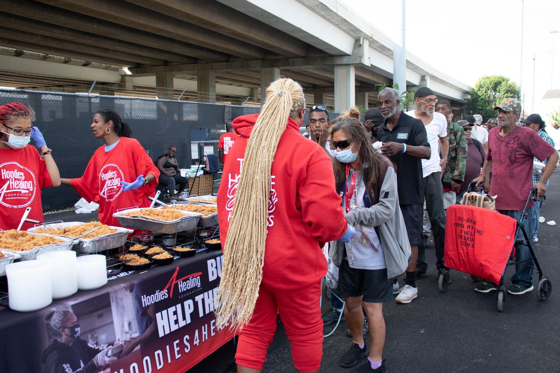 A group of people are standing around a table with food.