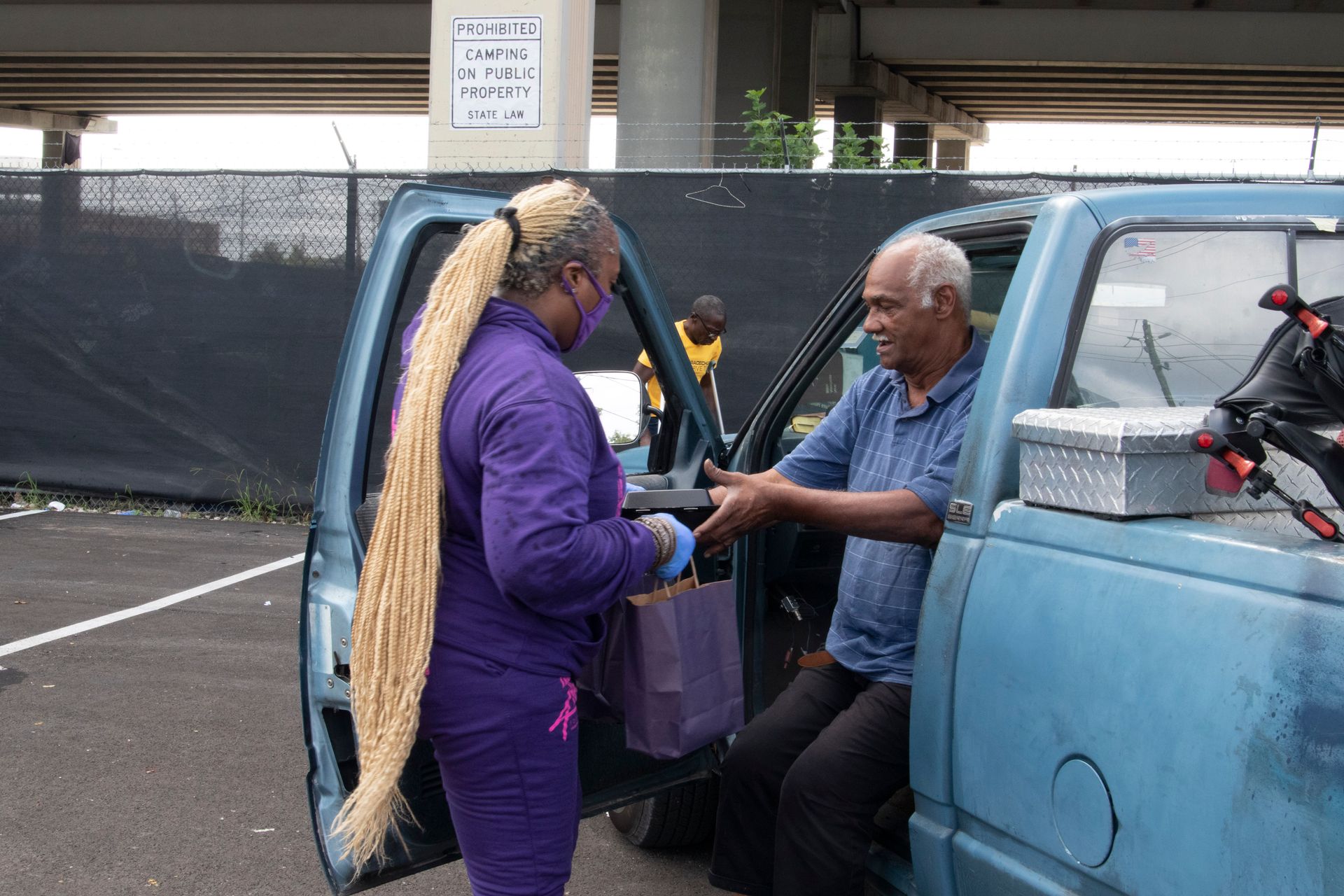 A man and a woman are standing next to a blue truck.