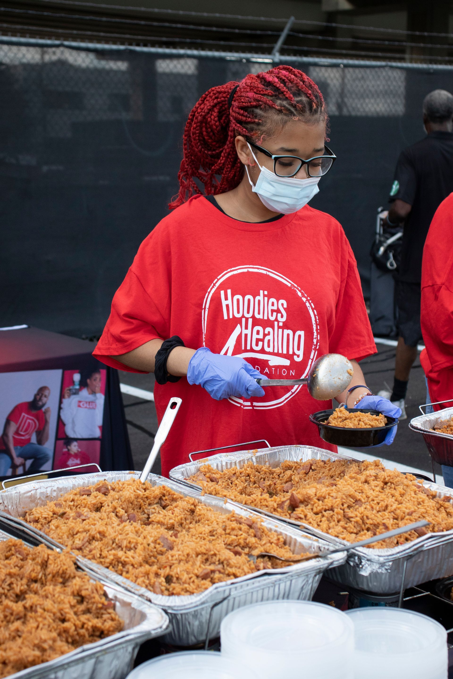 A woman wearing a mask is pouring food into a bowl.