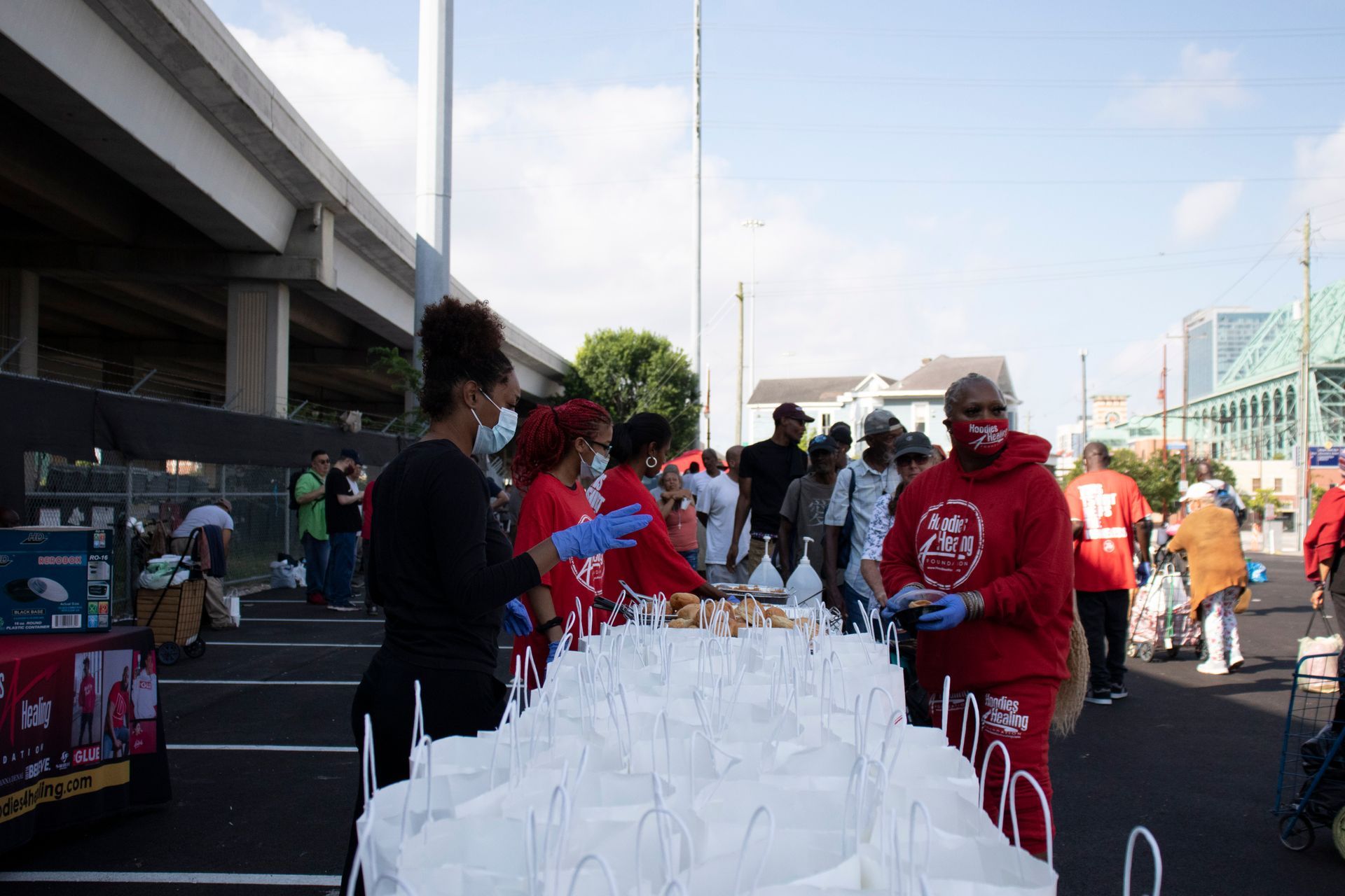 A group of people are standing around a table filled with bags of food.