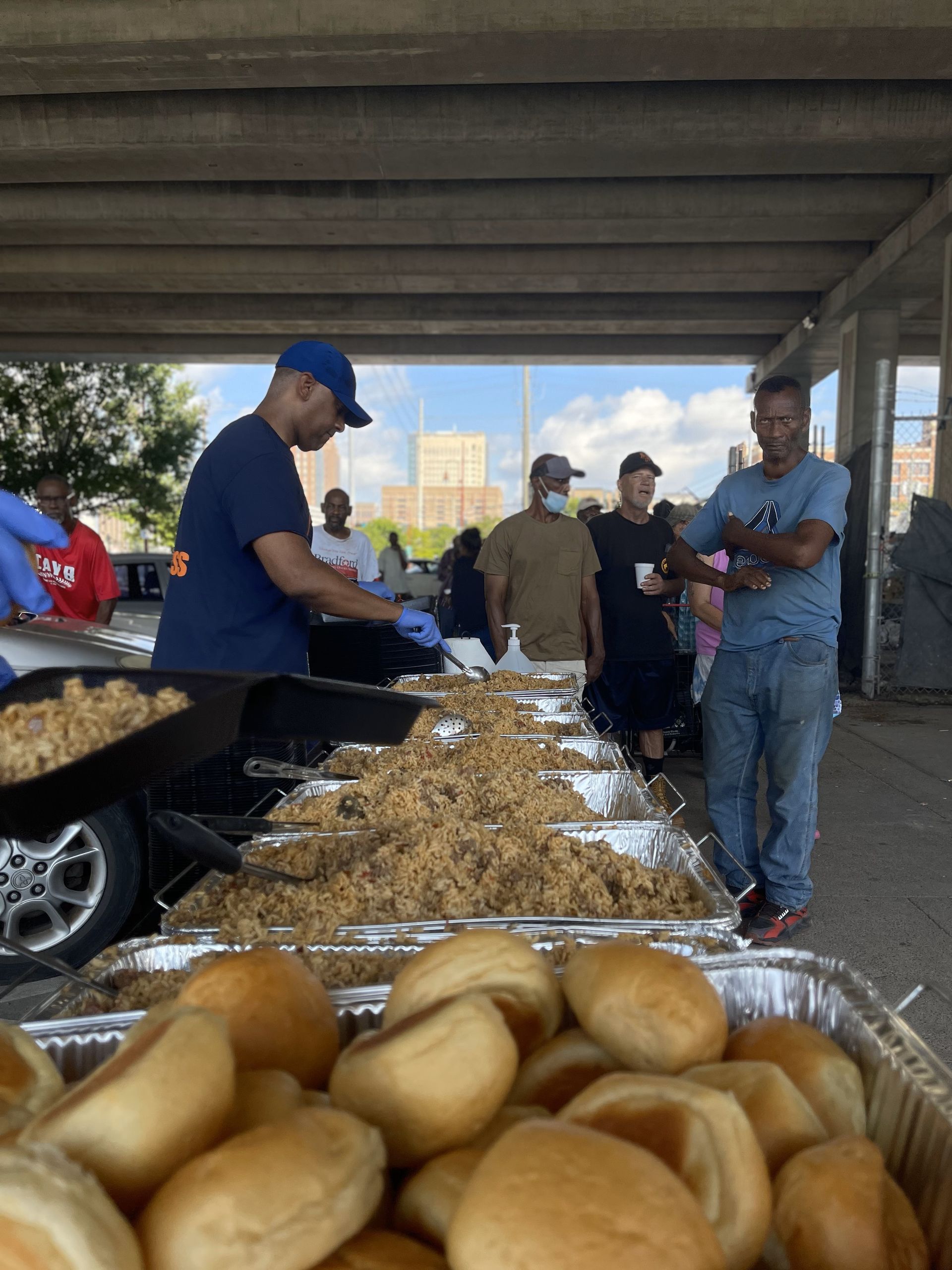 A group of people are standing around a tray of food.