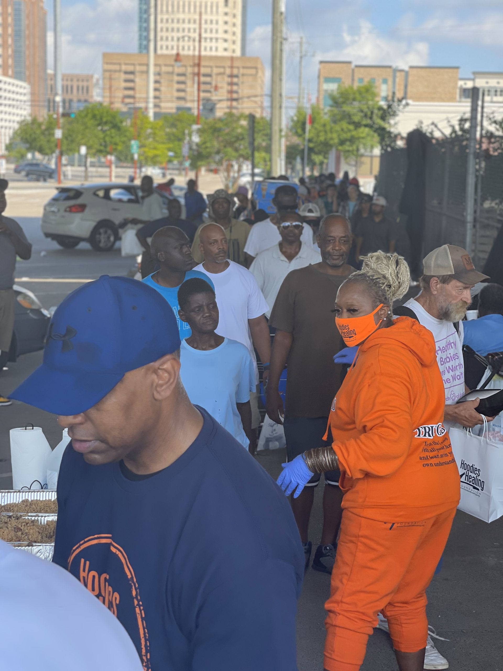 A woman wearing a mask is standing in a crowd of people.