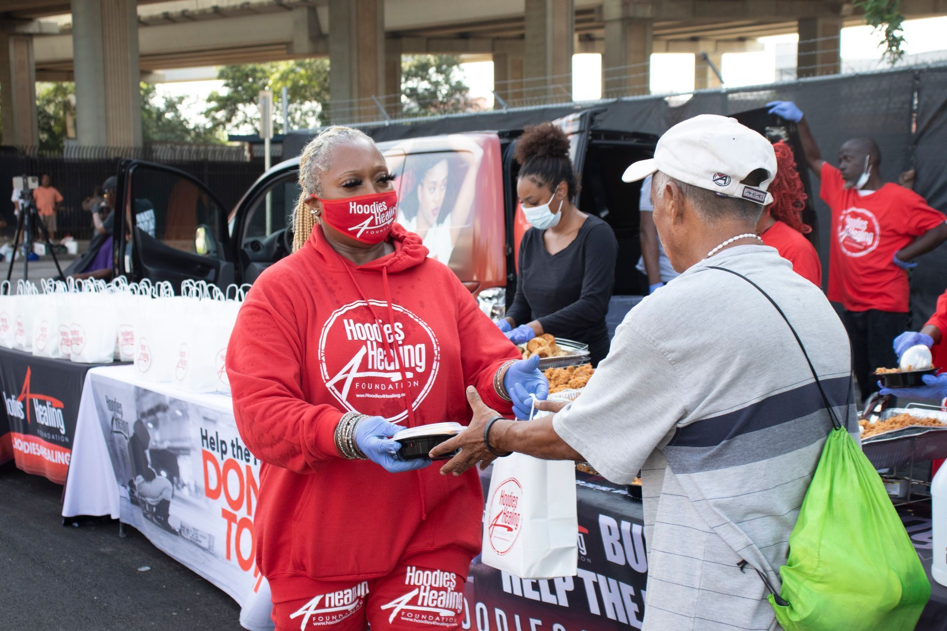 A woman in a red shirt is giving a man a plate of food.