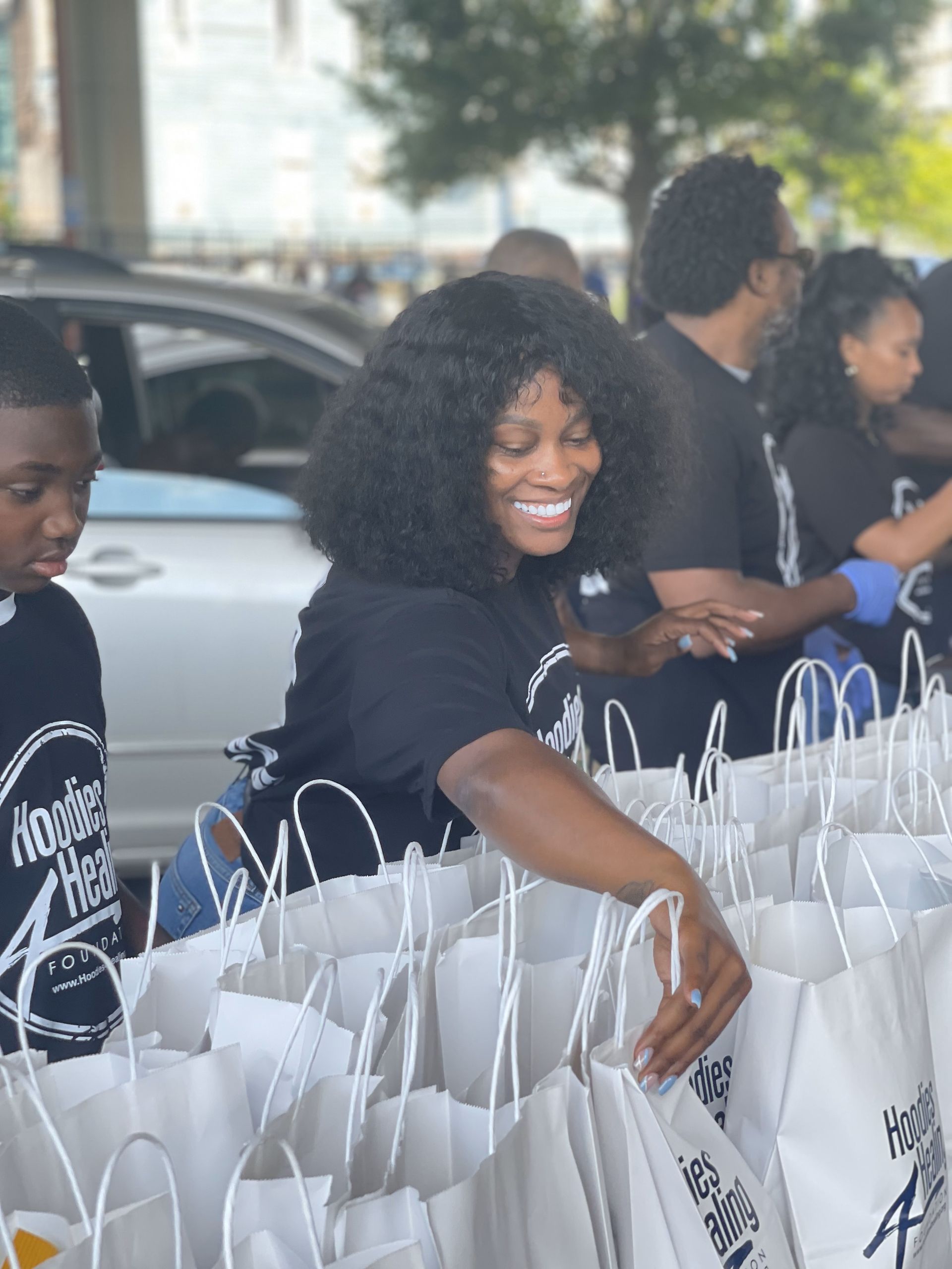 A woman is standing in front of a bunch of bags and smiling.