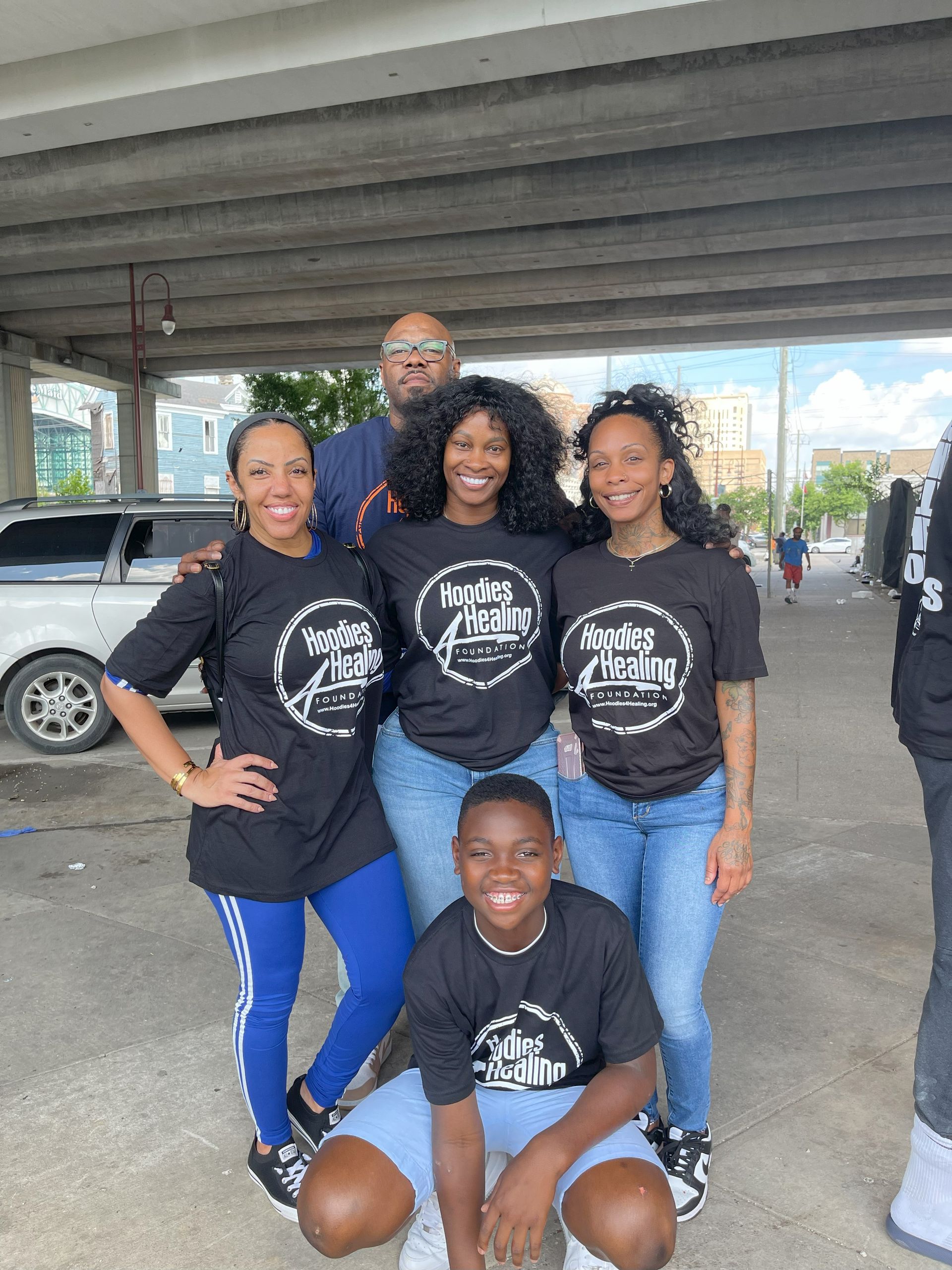 A group of people are posing for a picture under a bridge.