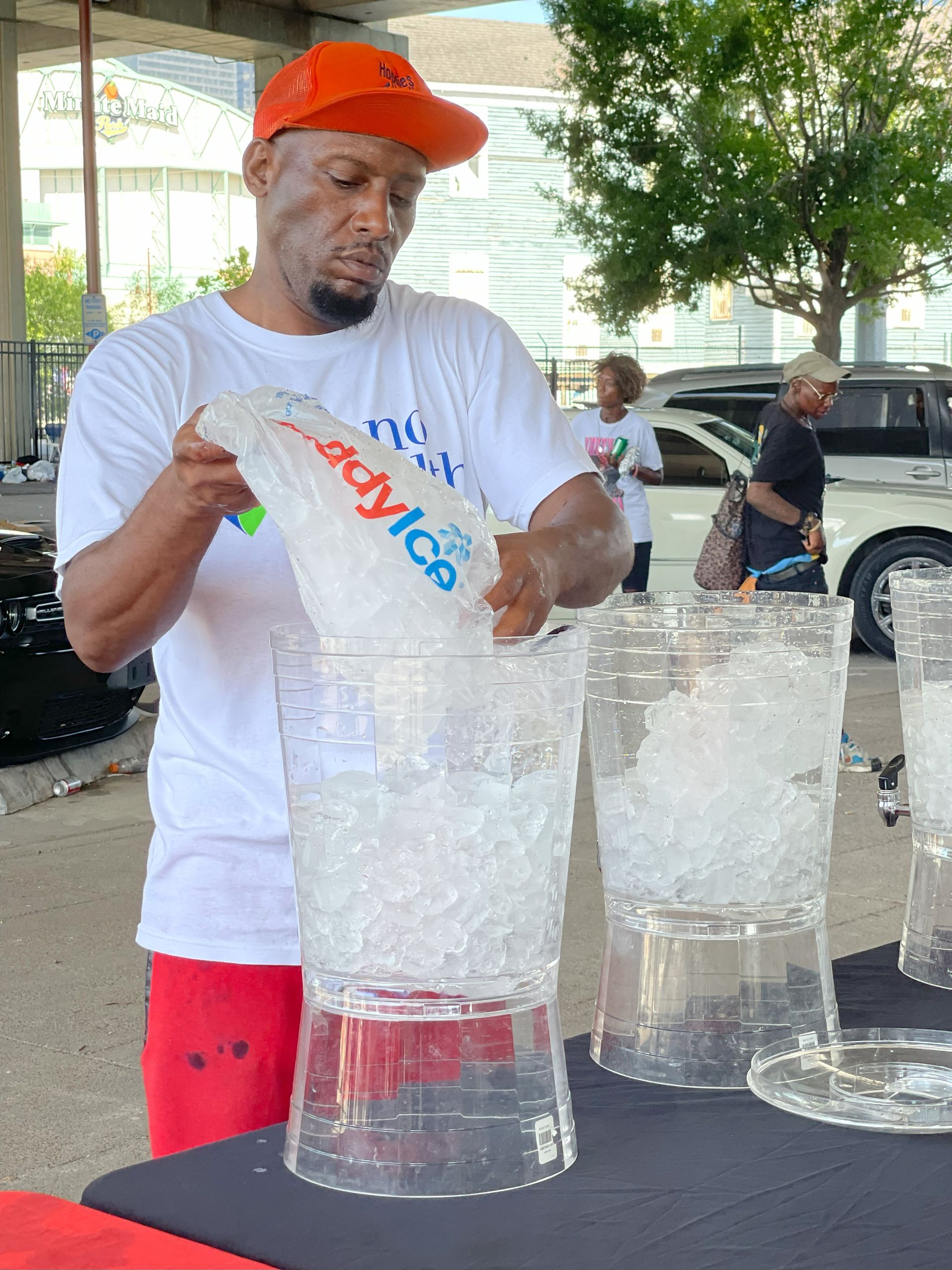 A man is pouring ice into a pitcher of water.
