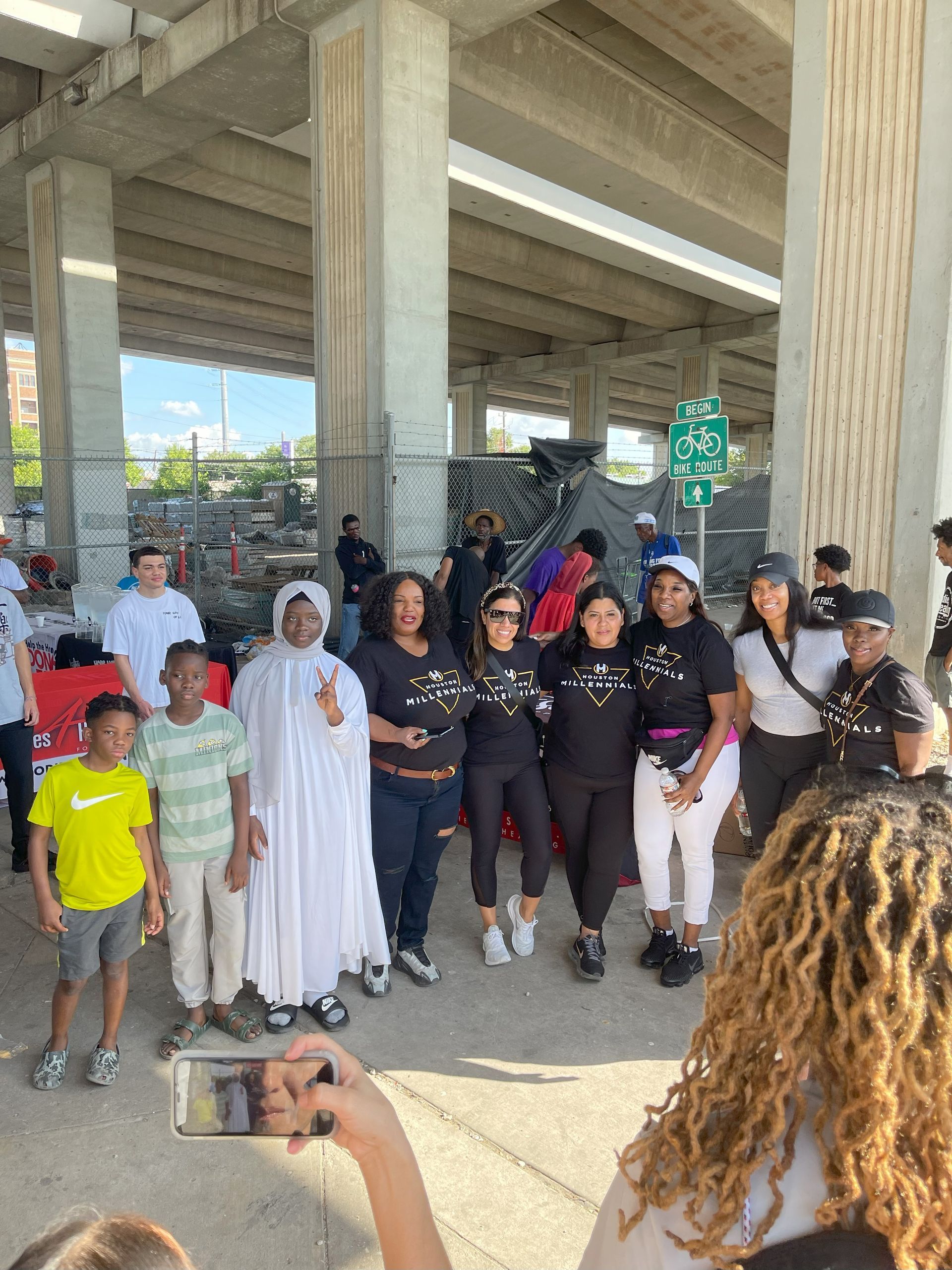 A group of people are posing for a picture under a bridge.