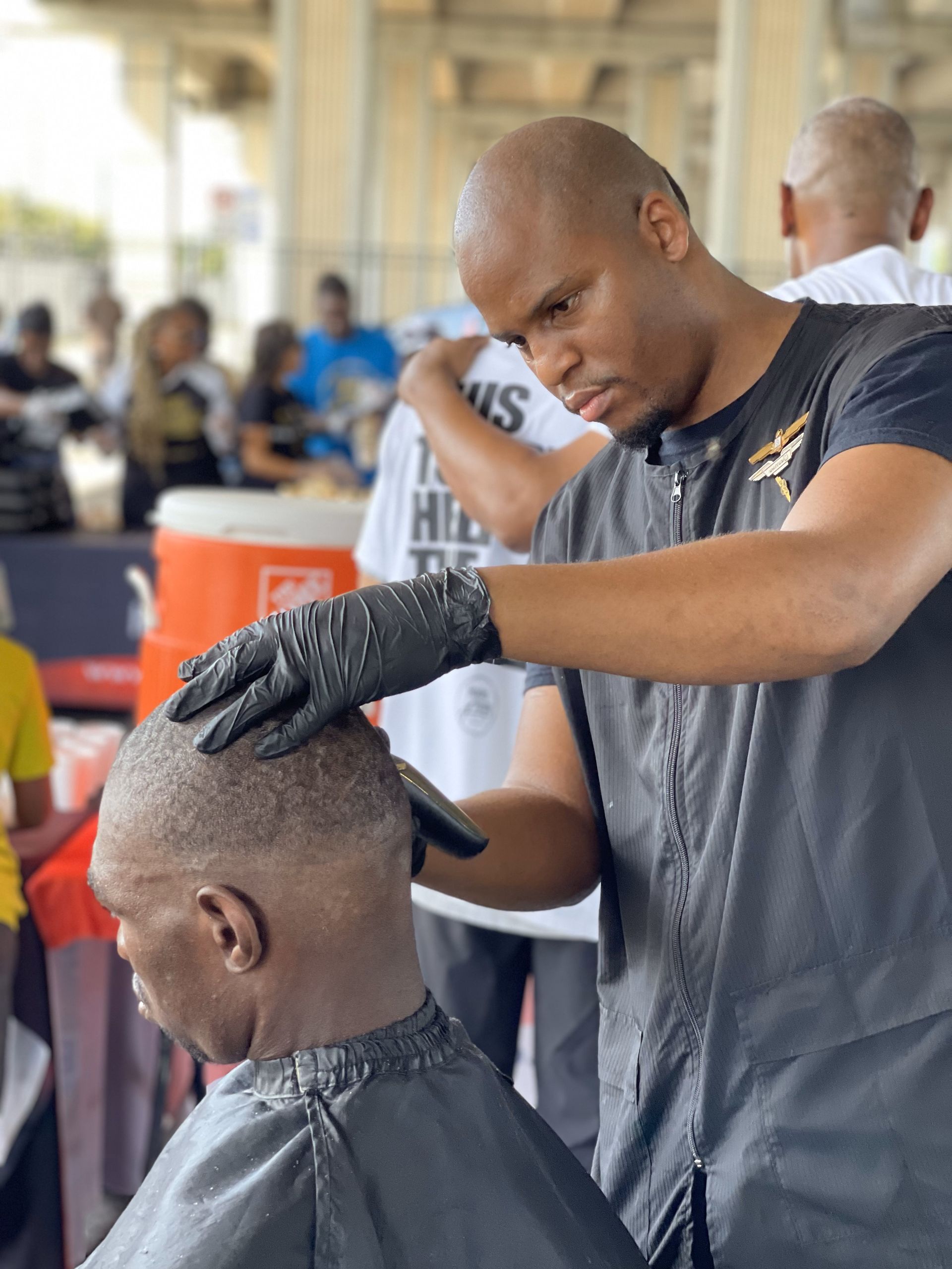 A man is getting his hair cut by a barber wearing gloves