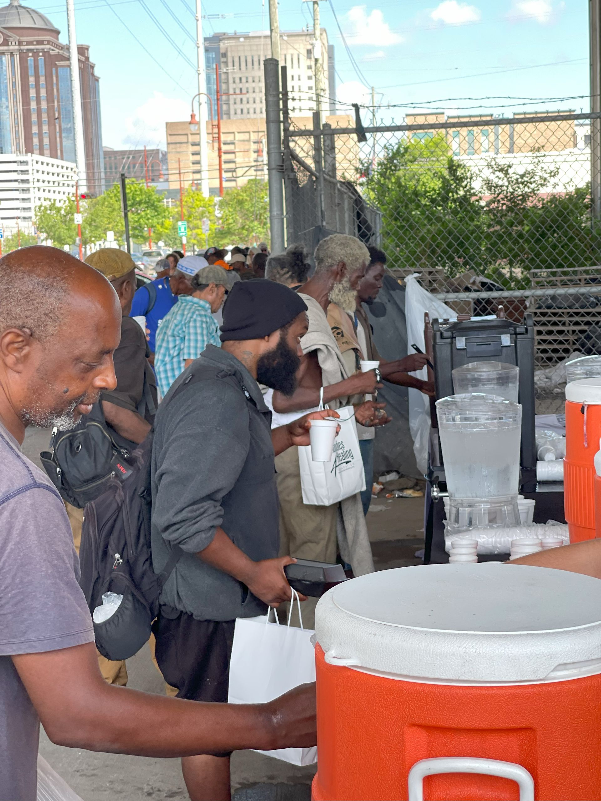 A group of people are standing around a large orange cooler.