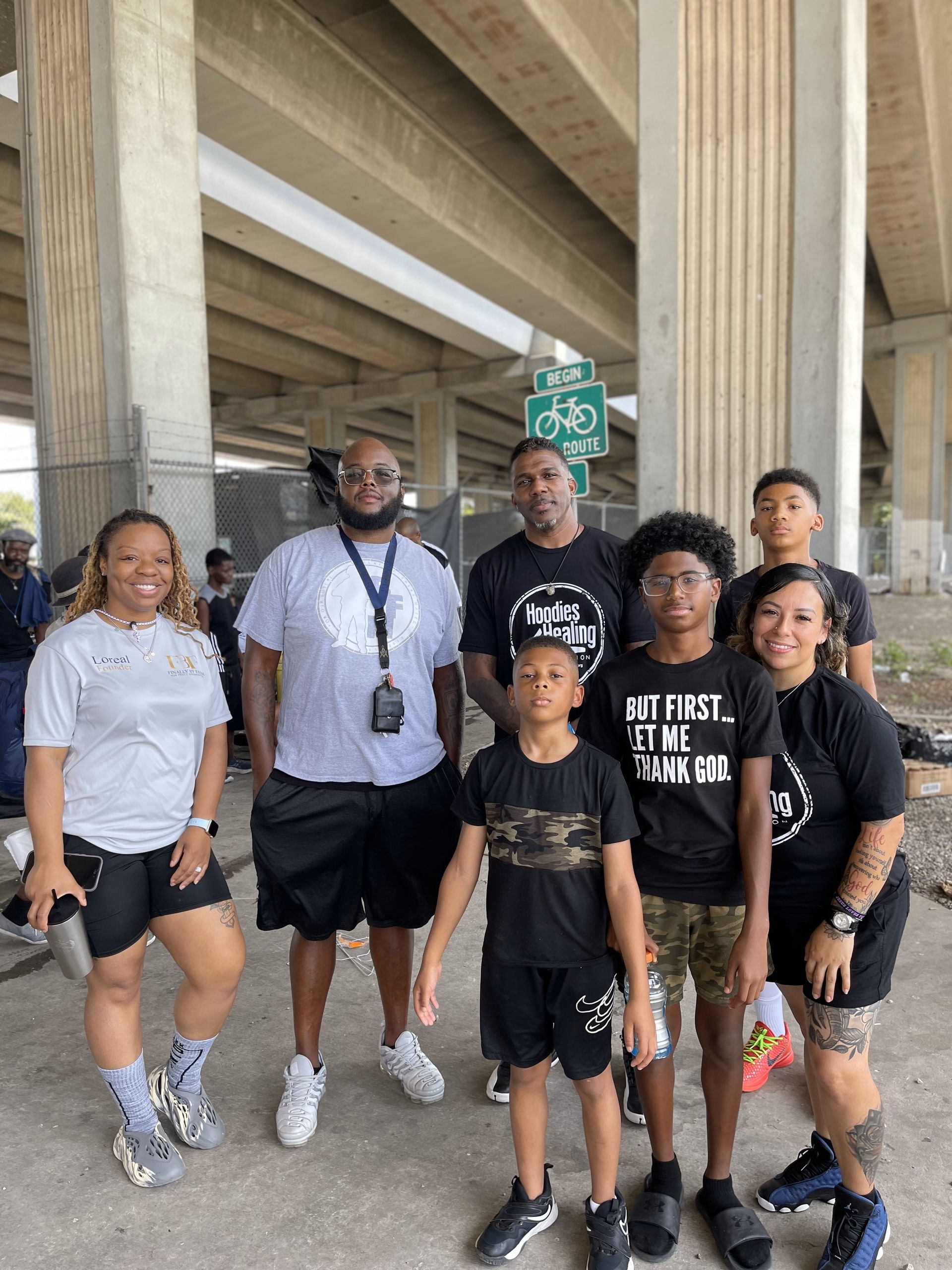 A group of people are posing for a picture under a bridge.