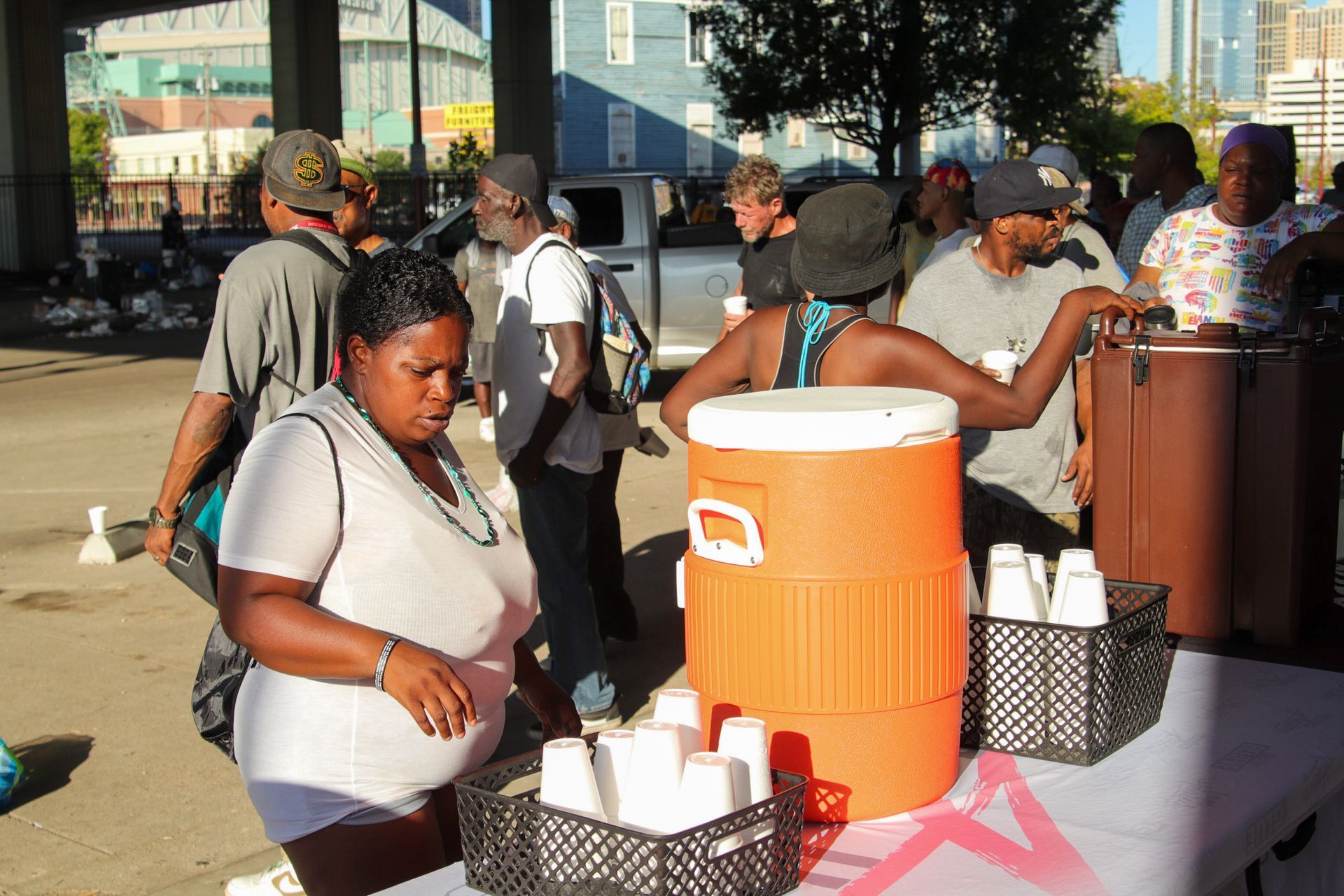 A group of people are gathered around a table with coolers and cups