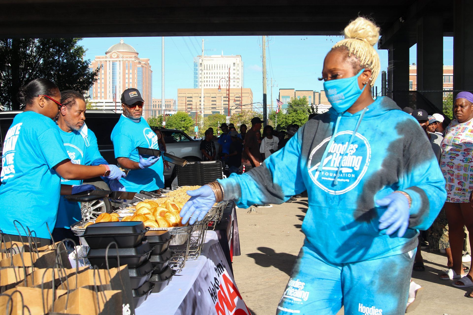 A woman wearing a mask and gloves is standing in front of a table.