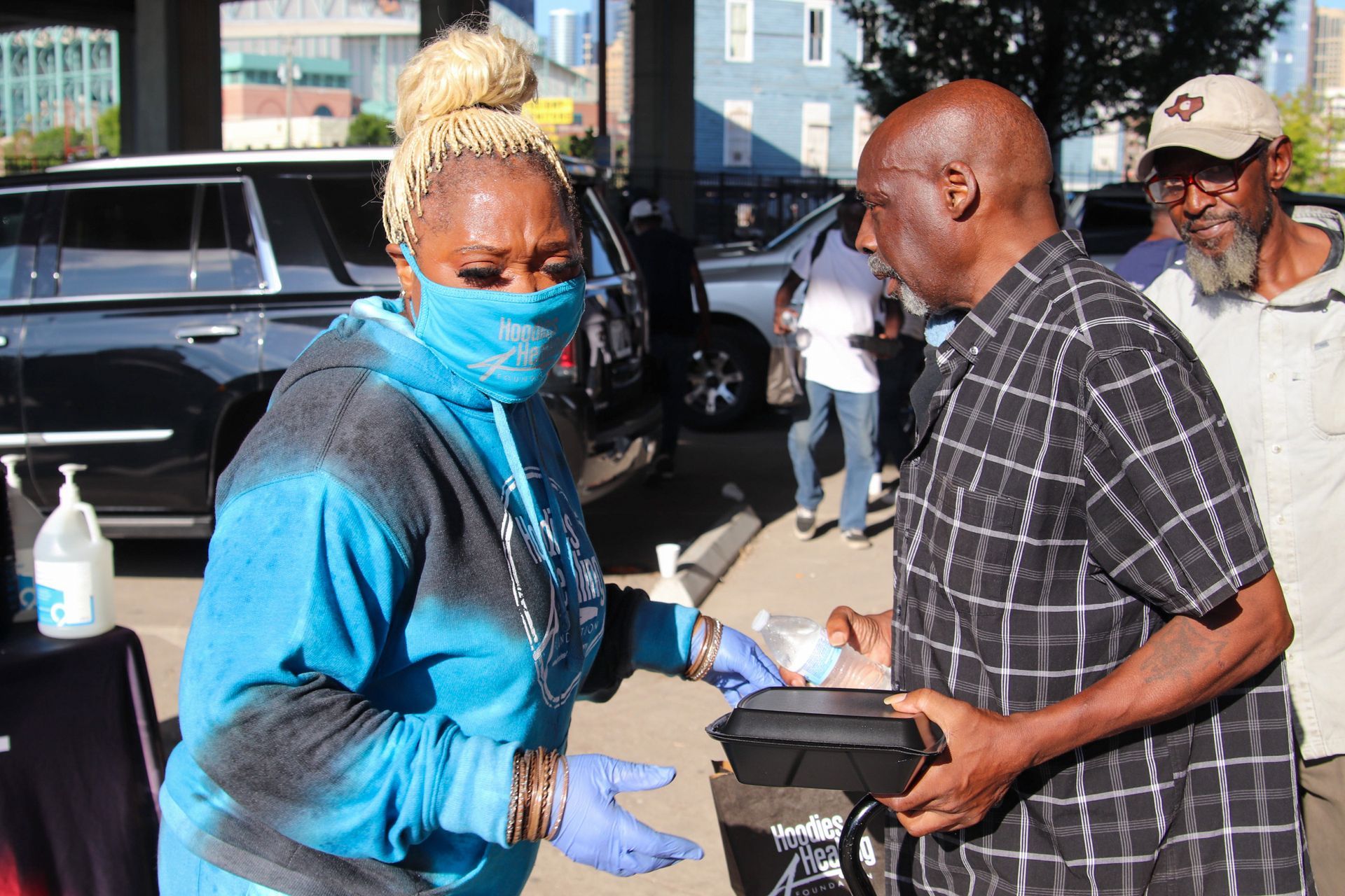 A woman wearing a mask is talking to a man in a parking lot.