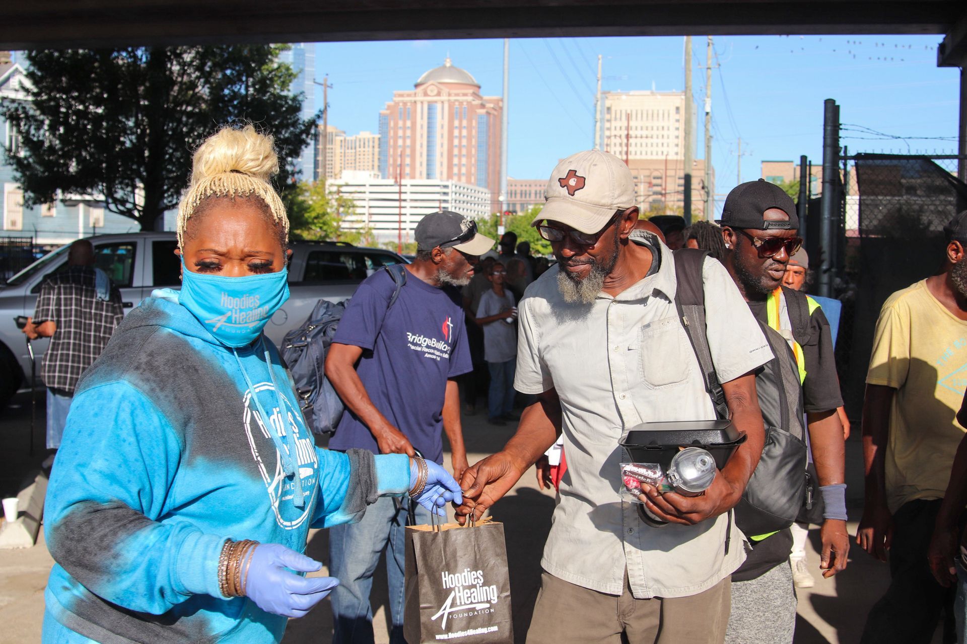 A group of people wearing masks and gloves are standing in a parking lot.