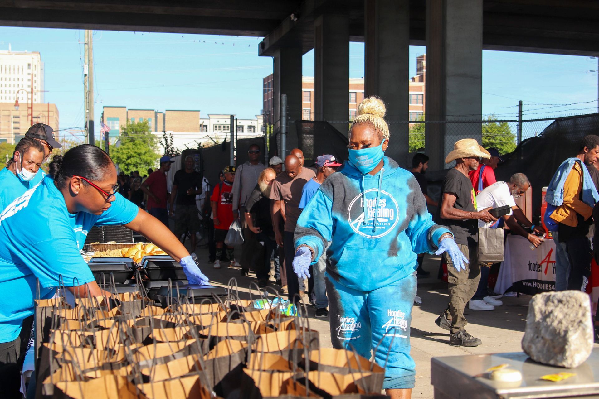 A group of people are standing around a table with boxes of food.